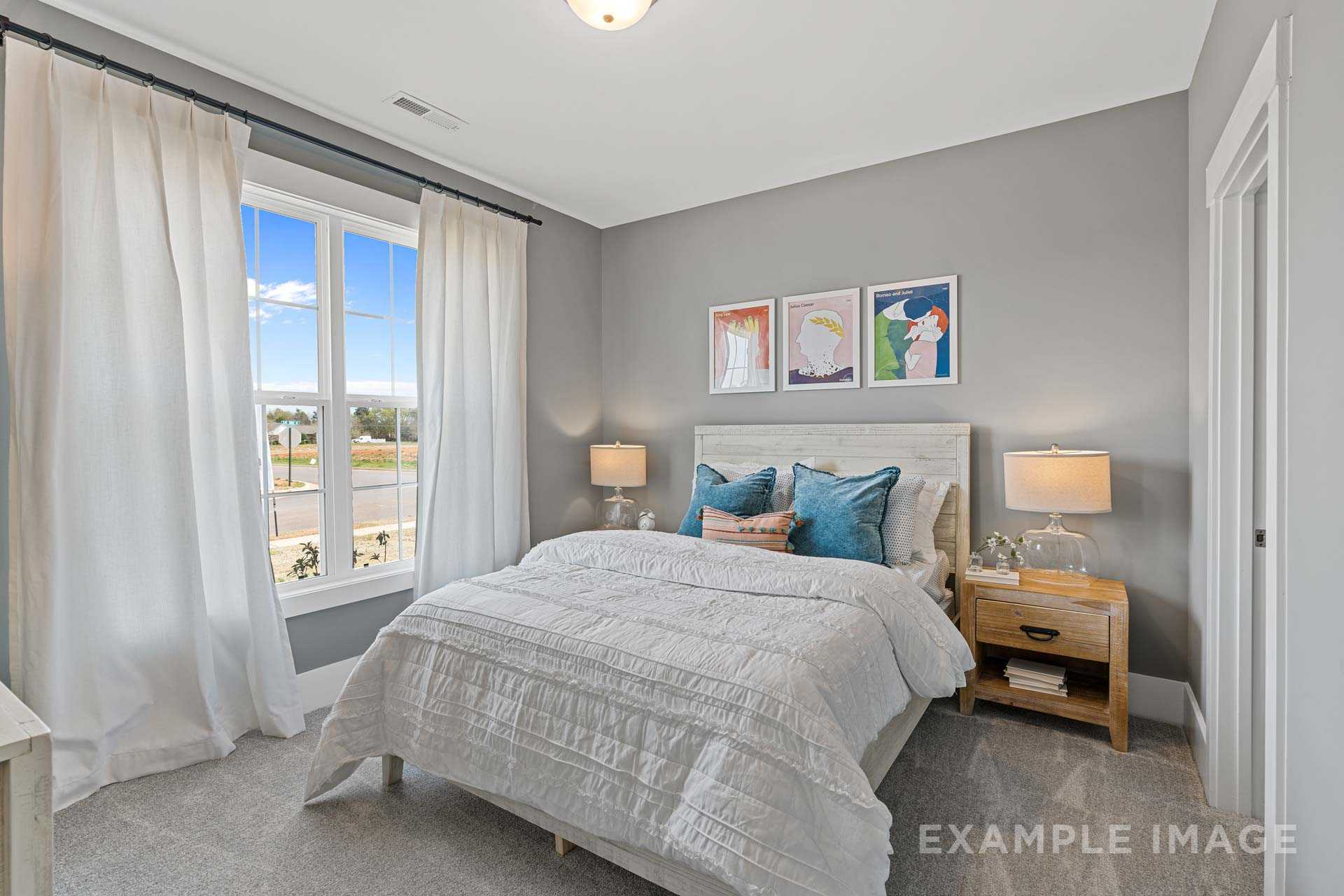 Serene master bedroom in The Rockford with white quilted bed, teal pillows, abstract wall art, and large window with sheer curtains
