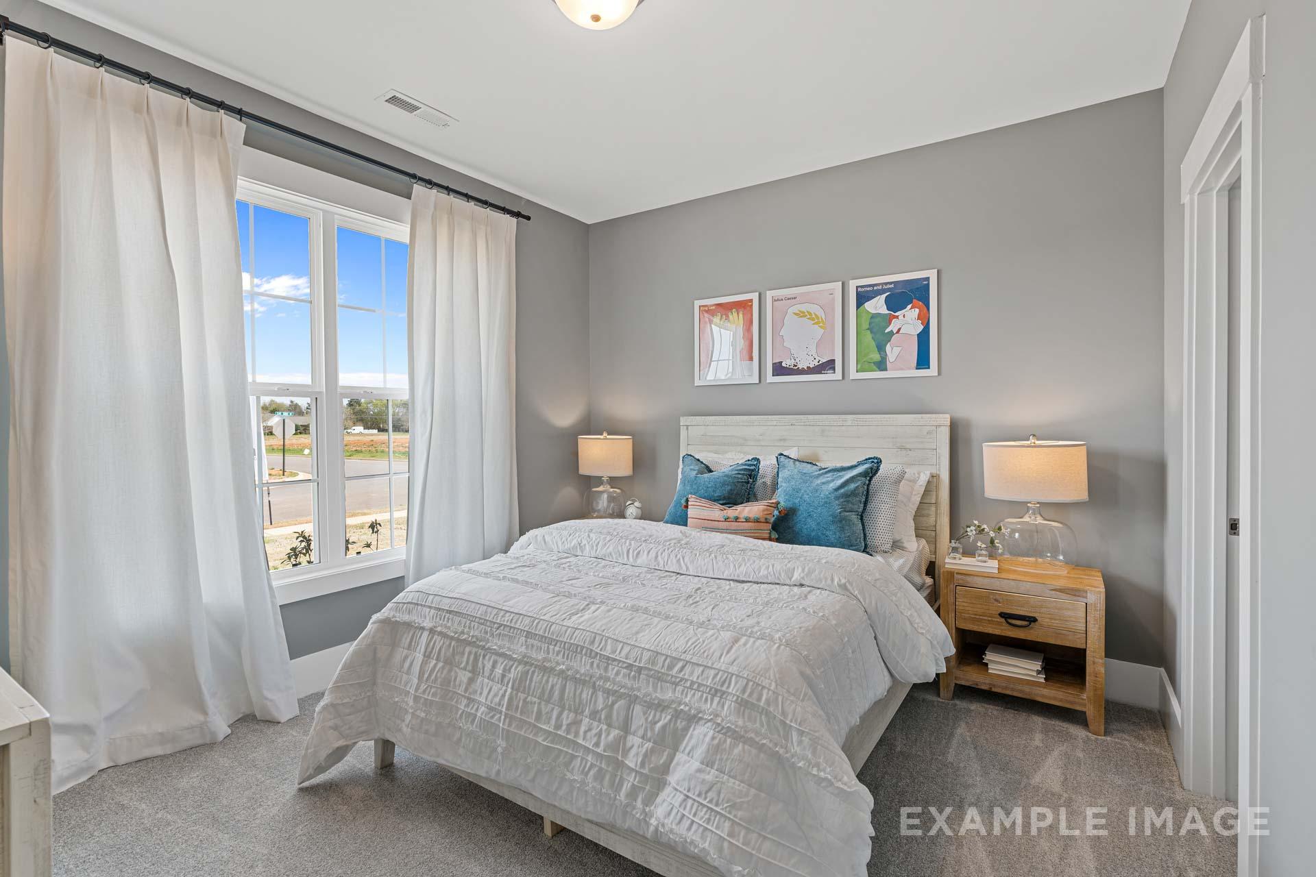 Serene master bedroom in The Rockford with white quilted bed, teal pillows, abstract wall art, and large window with sheer curtains
