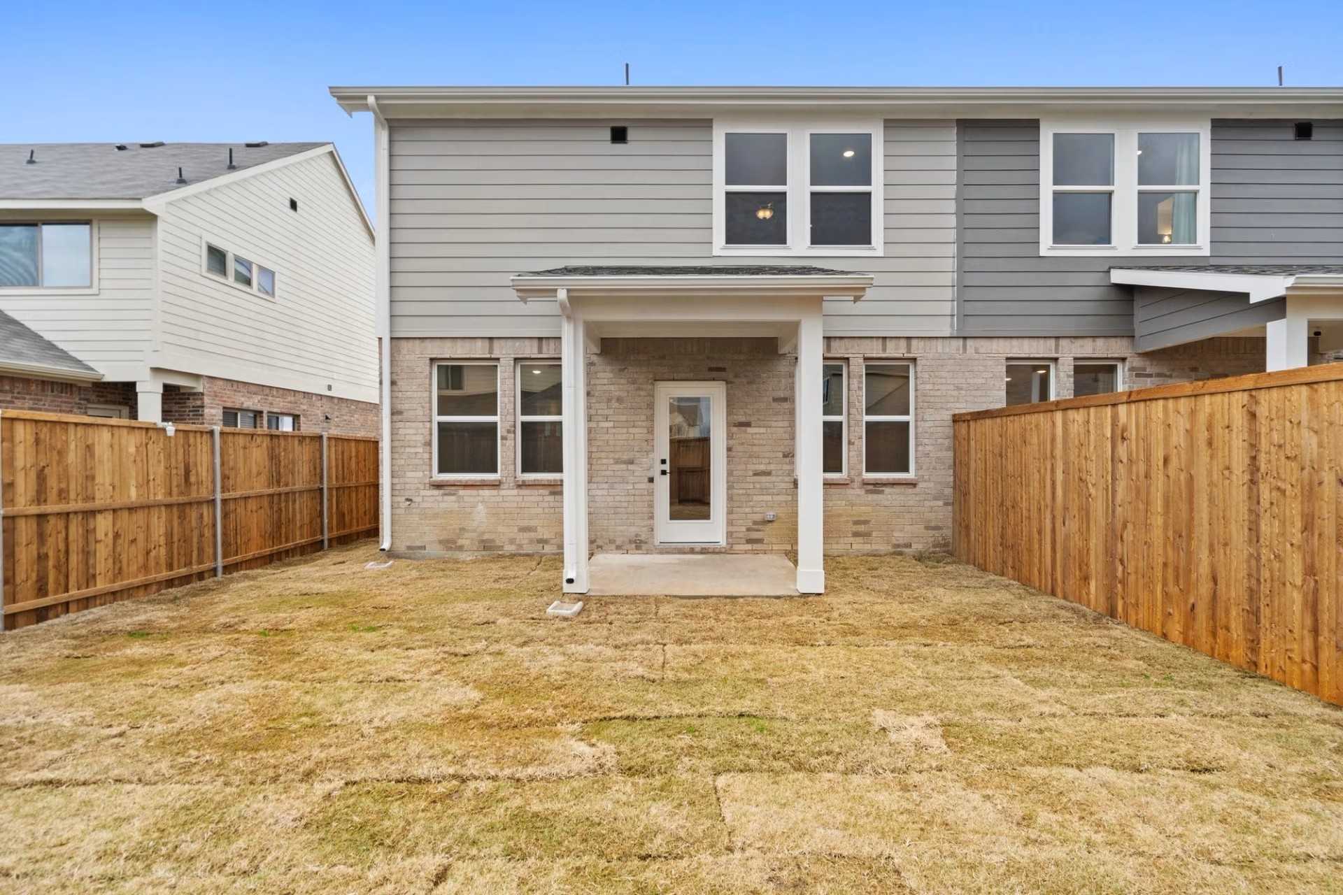 Rear view of The Wake D two-story home featuring covered patio and fenced backyard in Lake Park Villas, Wylie, Texas by Davidson Homes