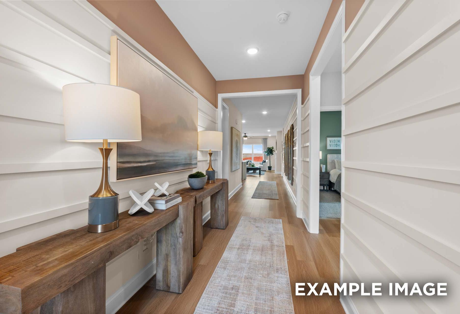 Spacious foyer in The Laurel M home featuring white shiplap walls, wooden consoles with lamps, and hardwood floors