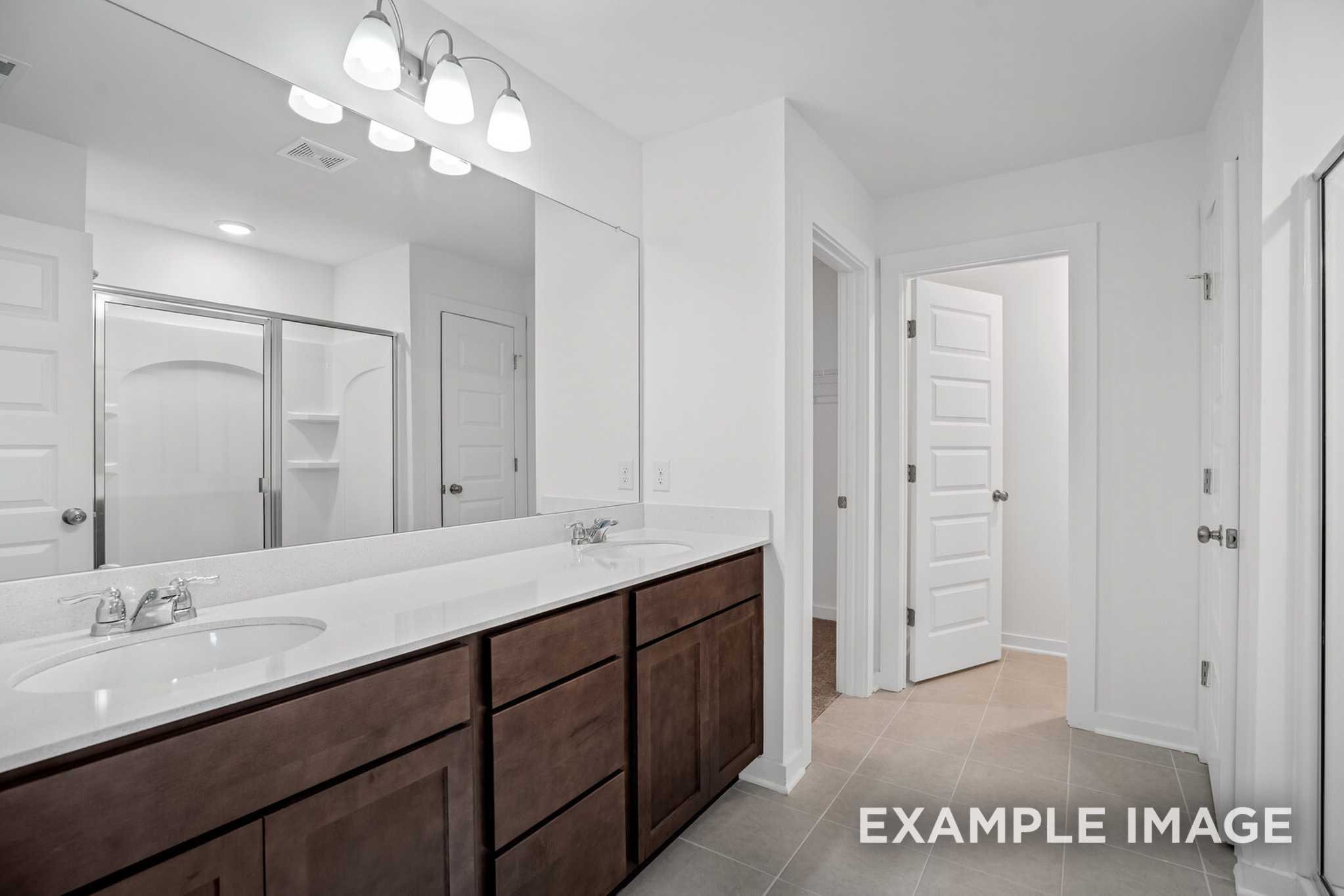 The Grayson C master bathroom with double sink vanity, dark shaker cabinets, frameless glass shower, and neutral tile floor