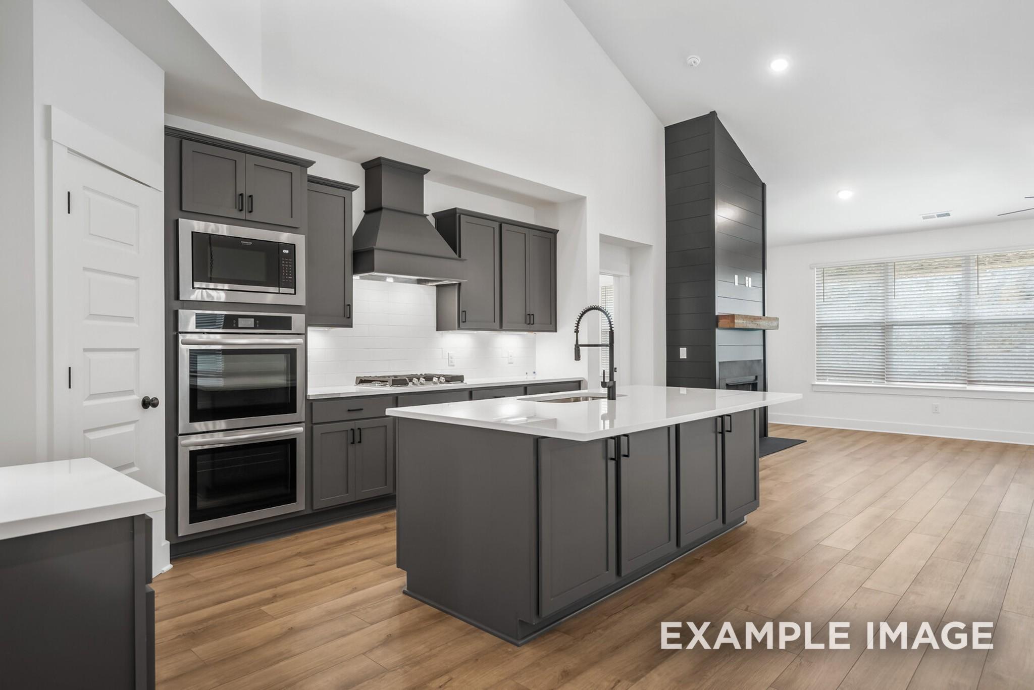 Modern kitchen with gray shaker cabinets, white quartz island, stainless double oven in Davidson Homes Ridgeport C, Gallatin, TN