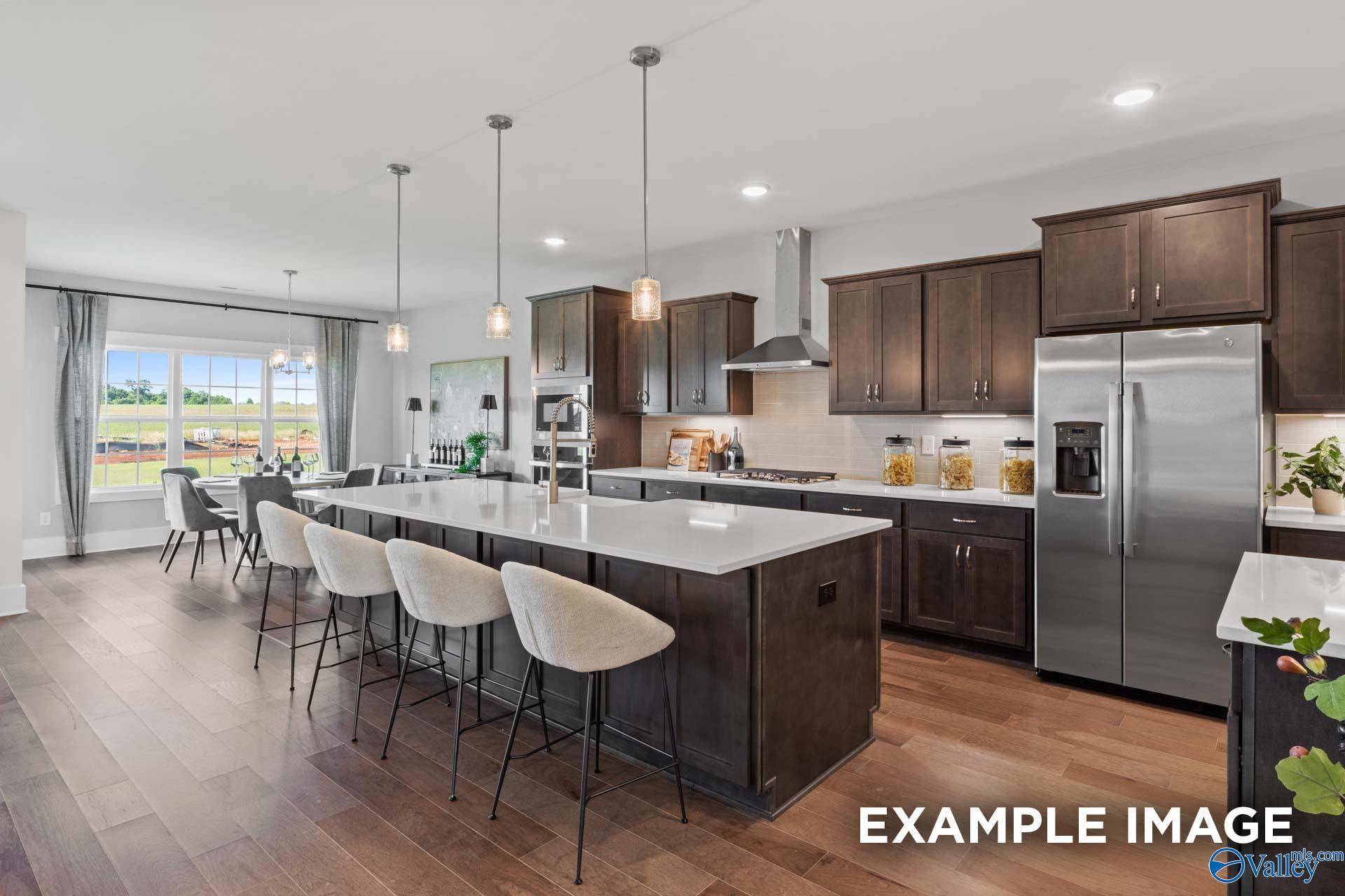 Modern open-concept kitchen with quartz island, dark cabinets, stainless appliances, and dining nook in The Finleigh home, Huntsville, AL