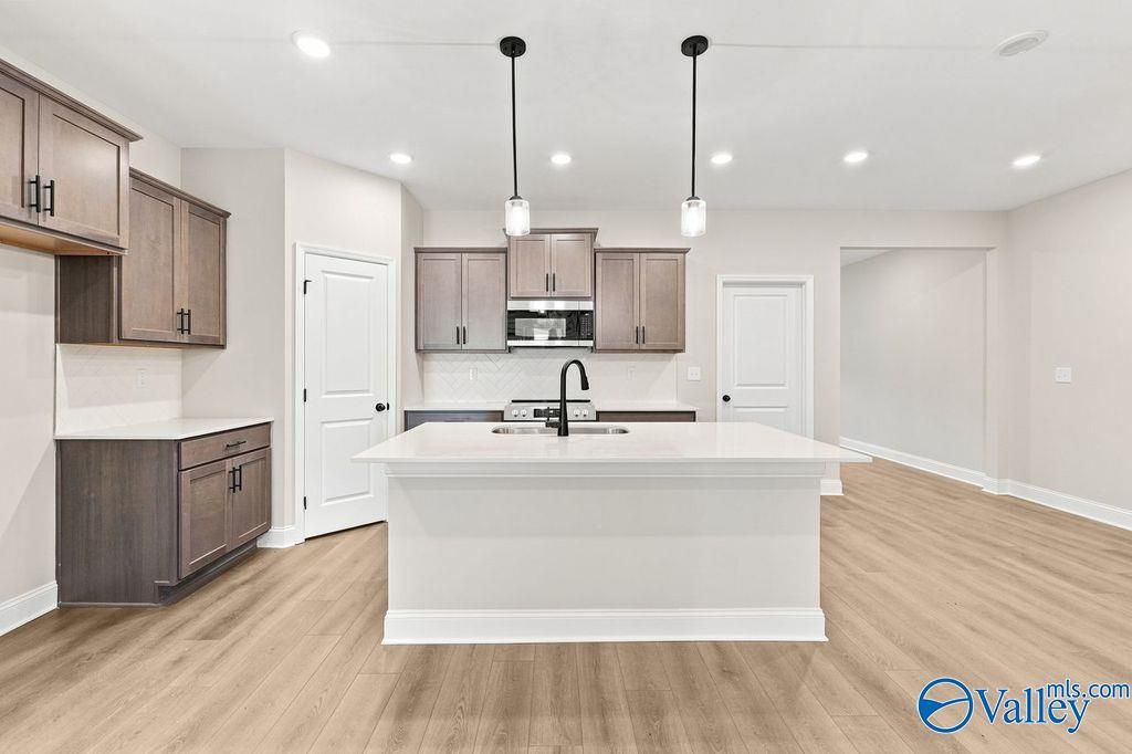 Modern kitchen with white island, gray cabinets, and pendant lighting in The Camilla C floor plan at The Retreat, Hartselle.