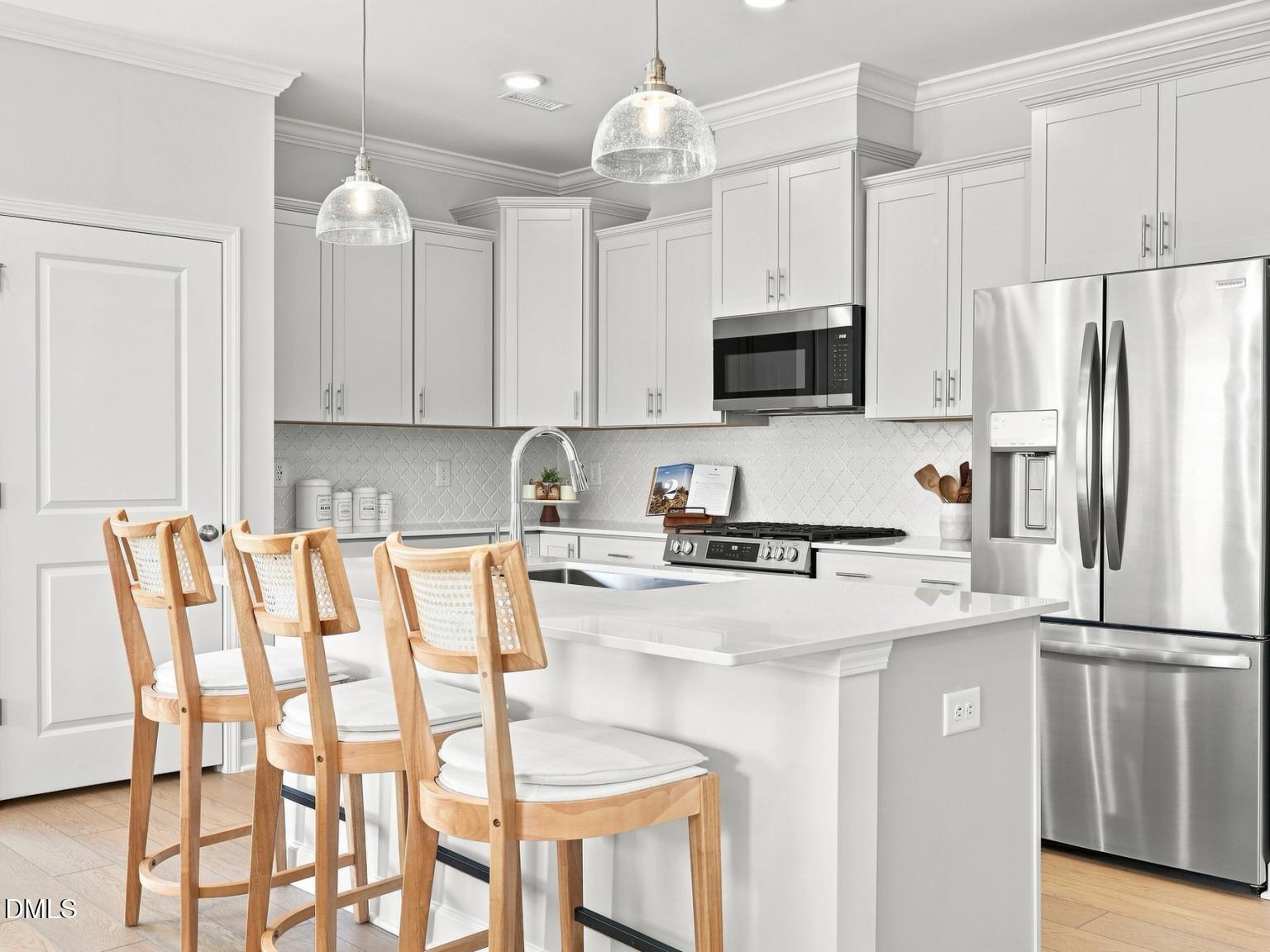 Modern kitchen with white cabinets, quartz island, and pendant lighting in The Daphne C floor plan, Woodland Crossing.