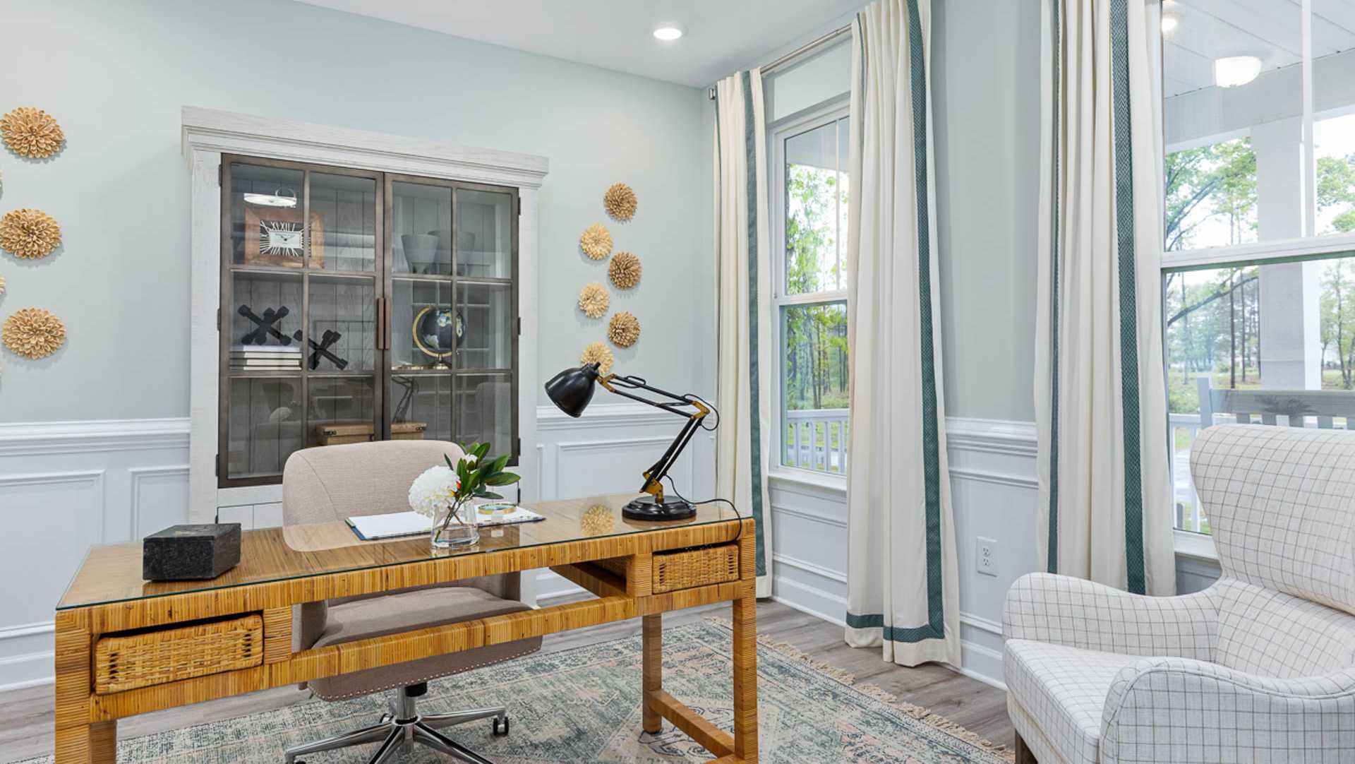 Cozy Davidson Homes office with wooden desk, swivel chair, glass cabinet, potted plant, and large windows in blue room
