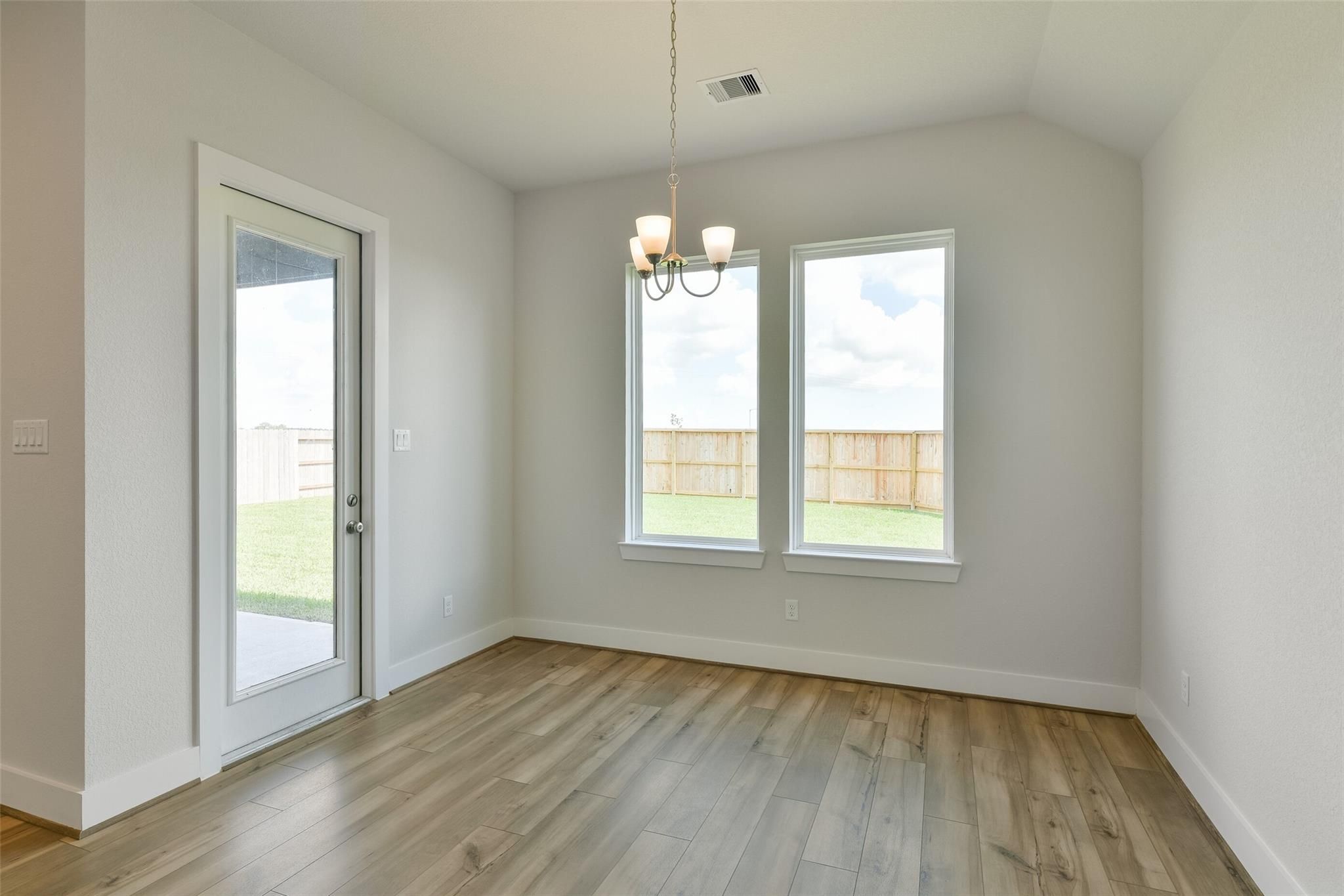 Bright dining room with chandelier, hardwood floors, French doors to grassy backyard in Davidson Homes The Edward A, Lago Mar, Texas City