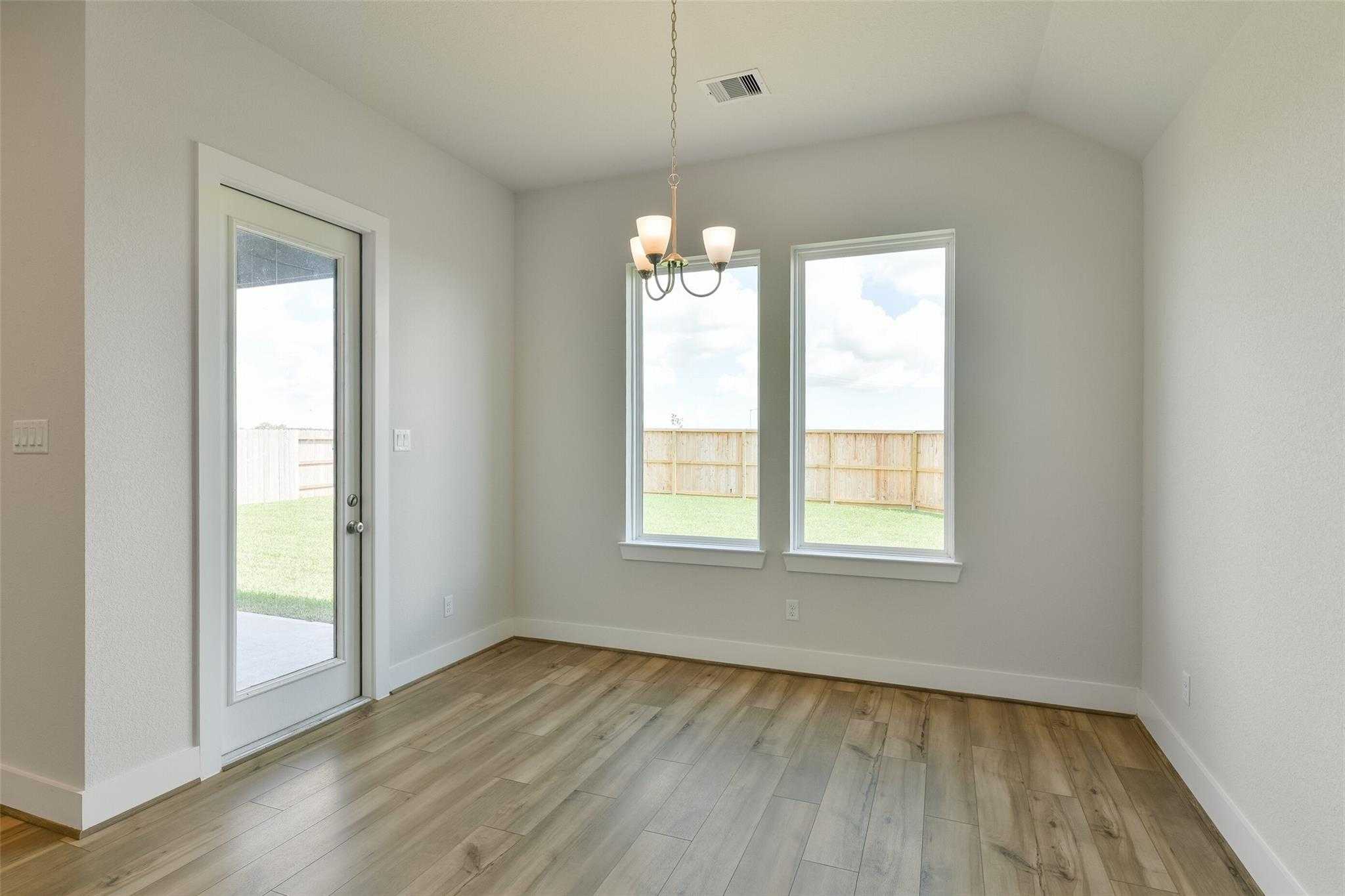 Bright dining room with chandelier, hardwood floors, French doors to grassy backyard in Davidson Homes The Edward A, Lago Mar, Texas City