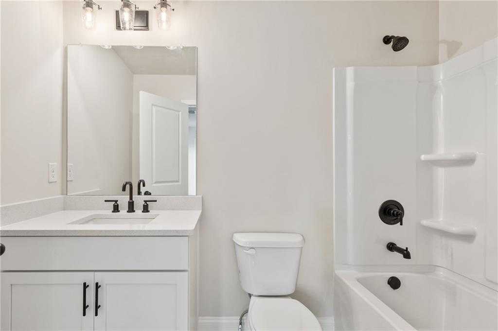 Modern guest bathroom featuring white vanity, single sink, bathtub shower combo, and black fixtures in Davidson Homes The Hickory B, Buford, GA