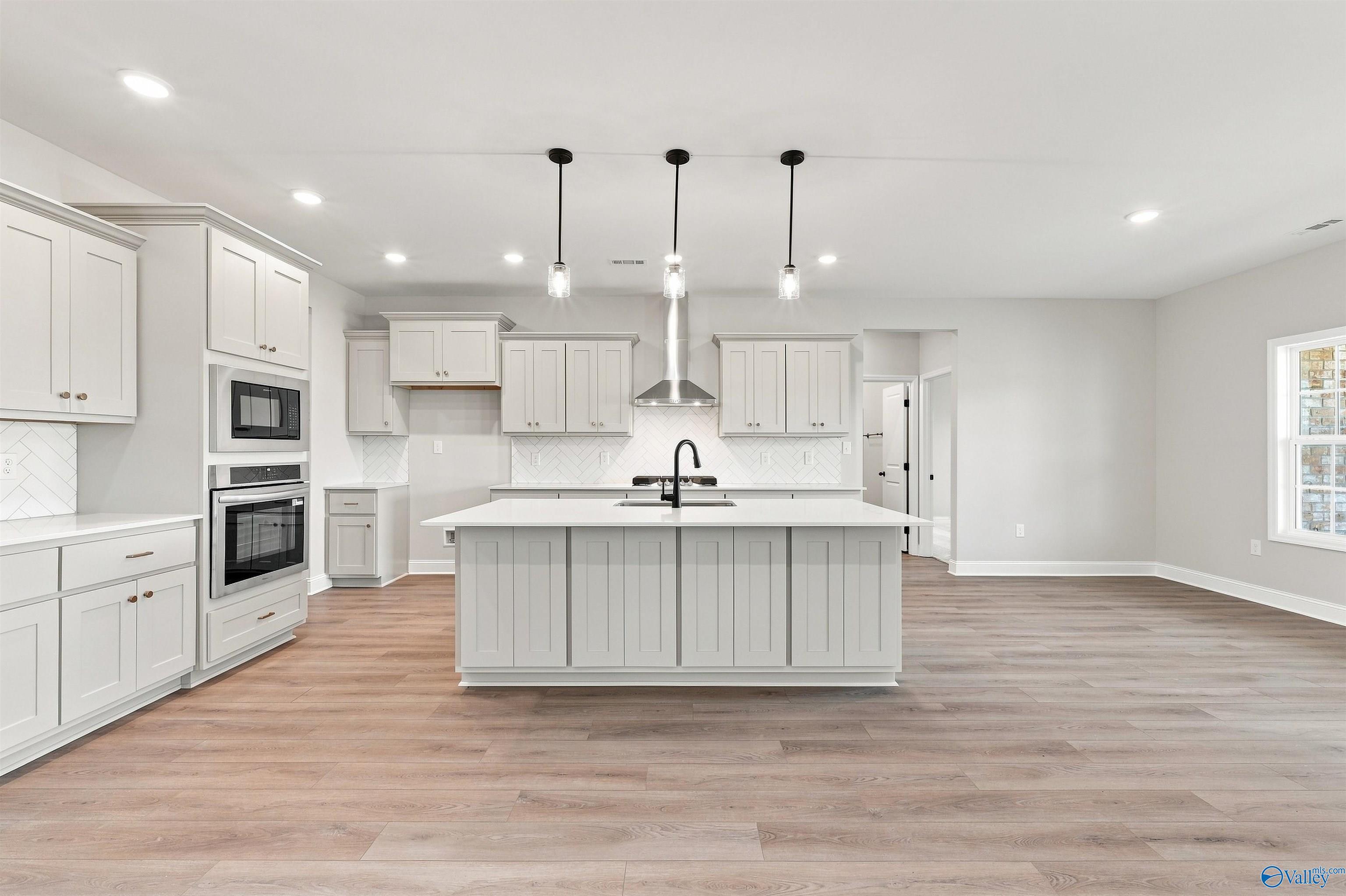 Modern kitchen with white island, pendant lighting, and stainless appliances in The Oxford floor plan, Kendall Farms, Toney.