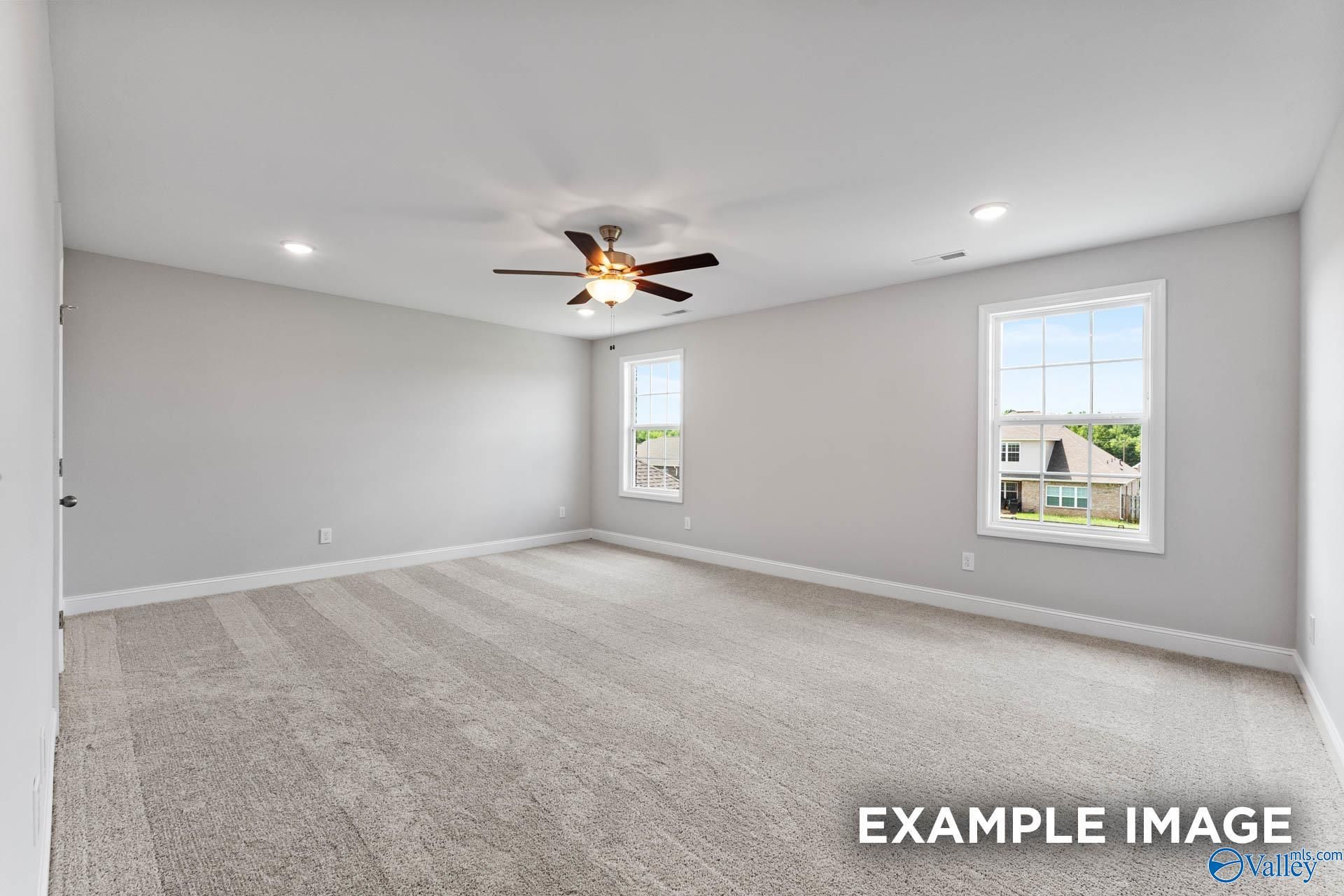 Spacious carpeted bedroom with ceiling fan, recessed lights, and large windows in Evermore Homes The Madison D, Madison, Alabama