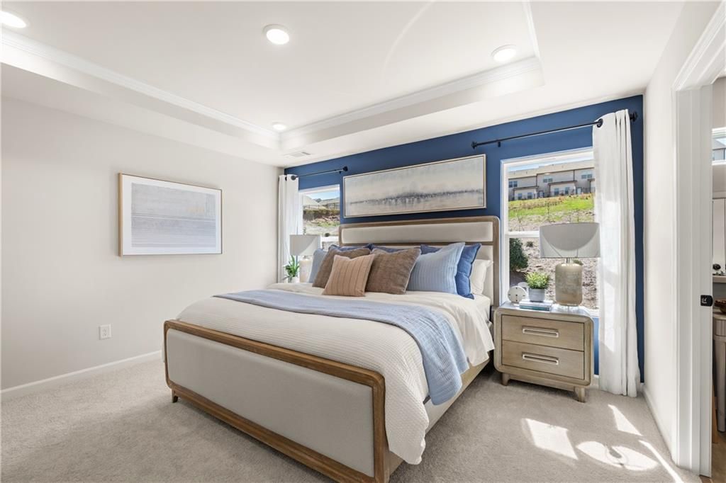 Elegant master bedroom with king bed, navy accent wall, abstract art, and large windows in Davidson Homes The Burton C, Canton GA