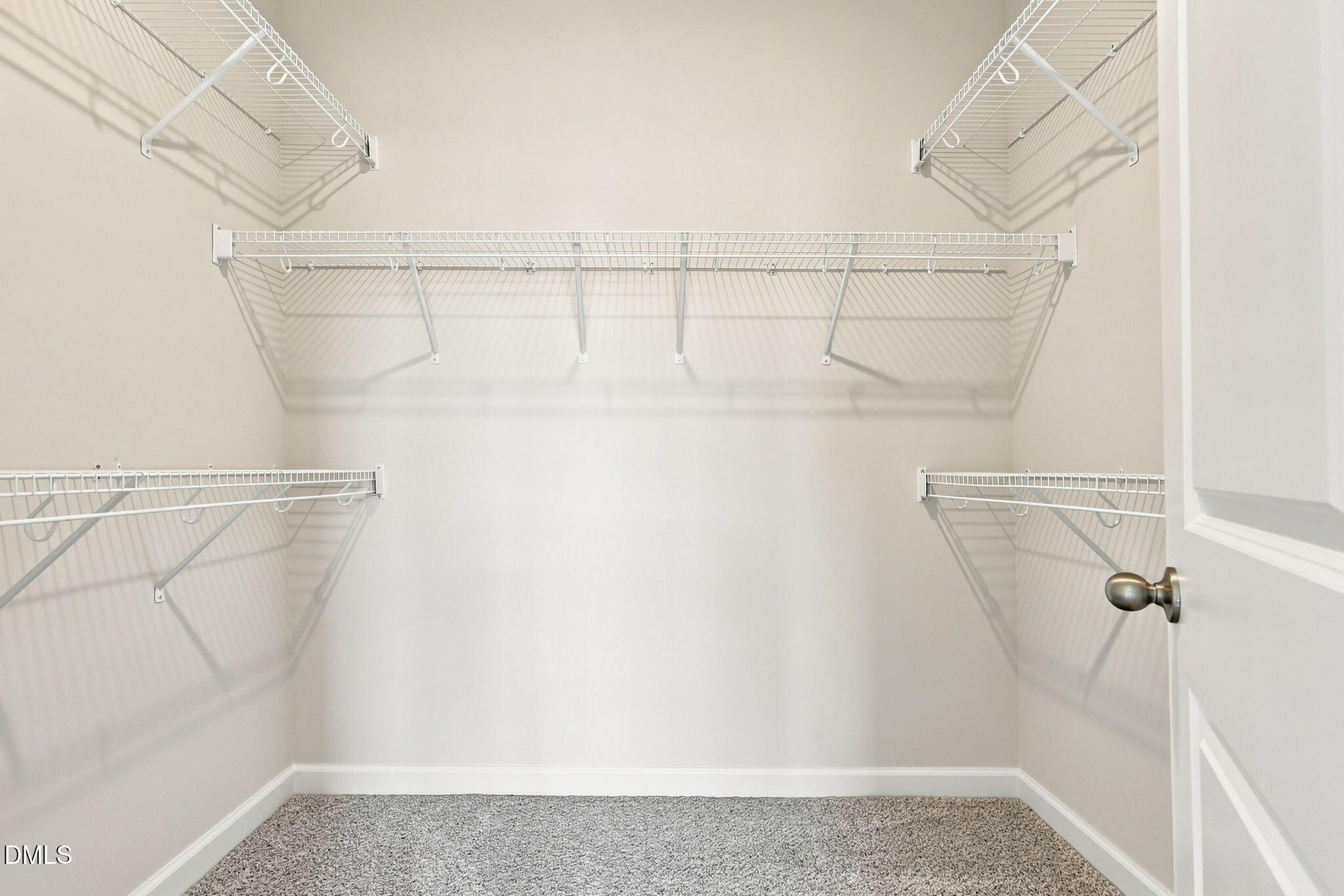 Walk-in closet with white wire shelving in The Magnolia B floor plan at Retreat at North Main in Lillington, NC.