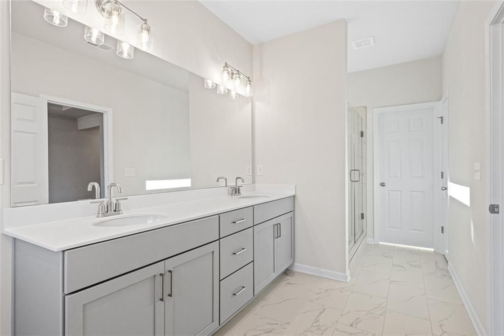 Modern master bathroom with double gray vanity, quartz counters, and porcelain tile floor in Davidson Homes The Glenwood C, Wehunt Meadows, Hoschton