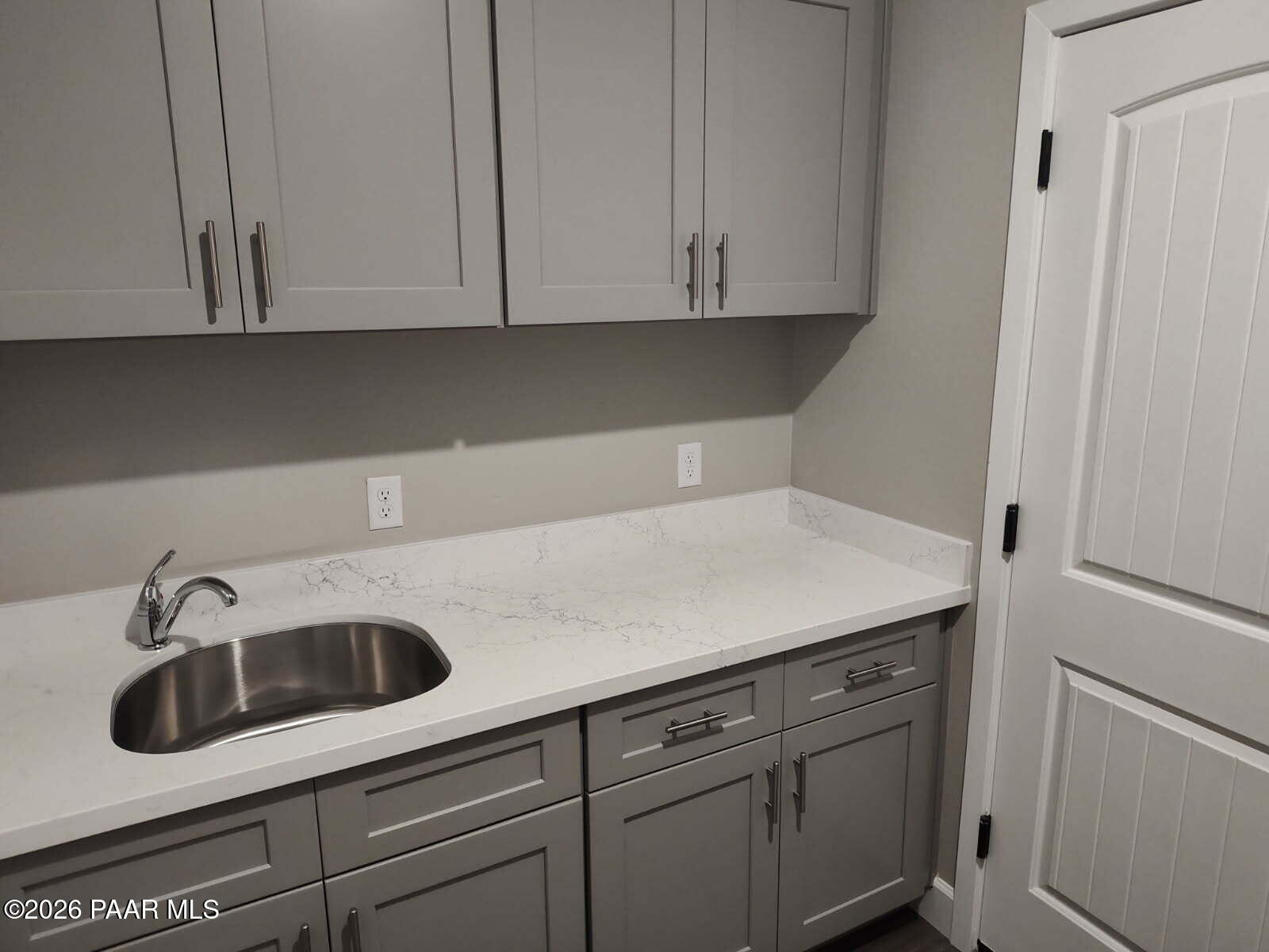 Modern laundry room featuring gray shaker cabinets, white quartz countertop, stainless sink in Davidson Homes The Harmony C, Prescott Valley