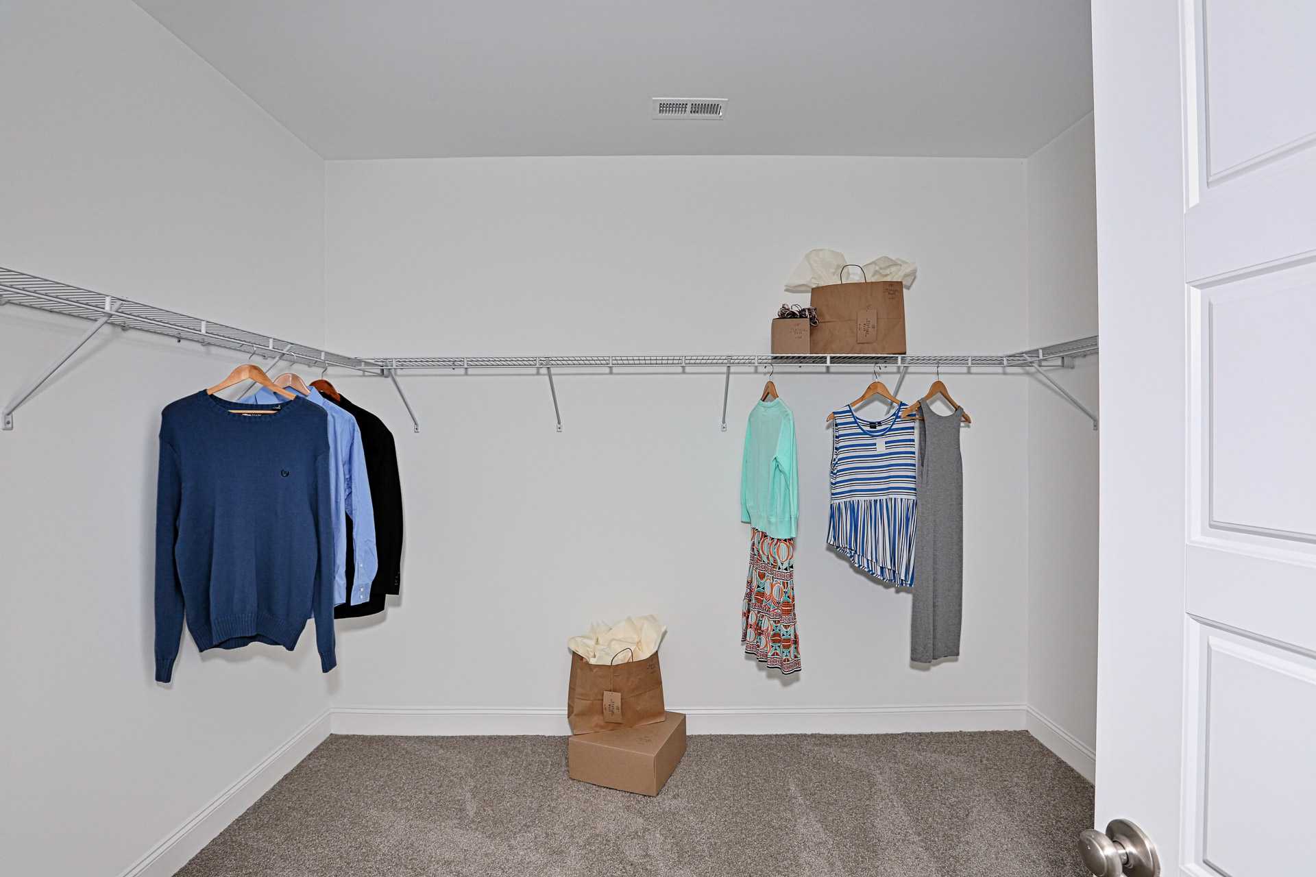 Spacious walk-in closet in Stone Creek Phase II Cullman Alabama home with wire shelving hanging sweaters blouses dresses storage boxes