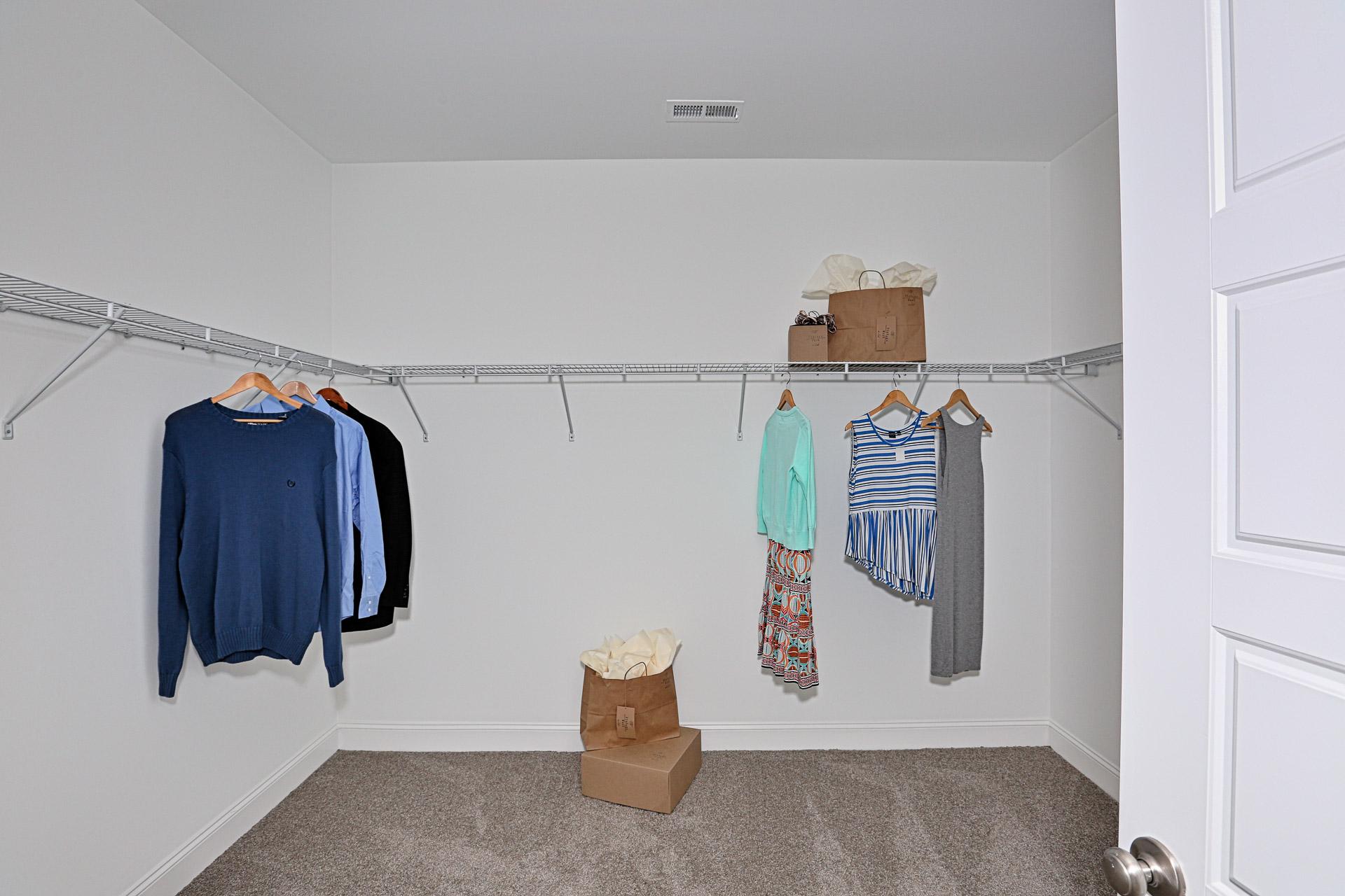 Spacious walk-in closet in Stone Creek Phase II Cullman Alabama home with wire shelving hanging sweaters blouses dresses storage boxes