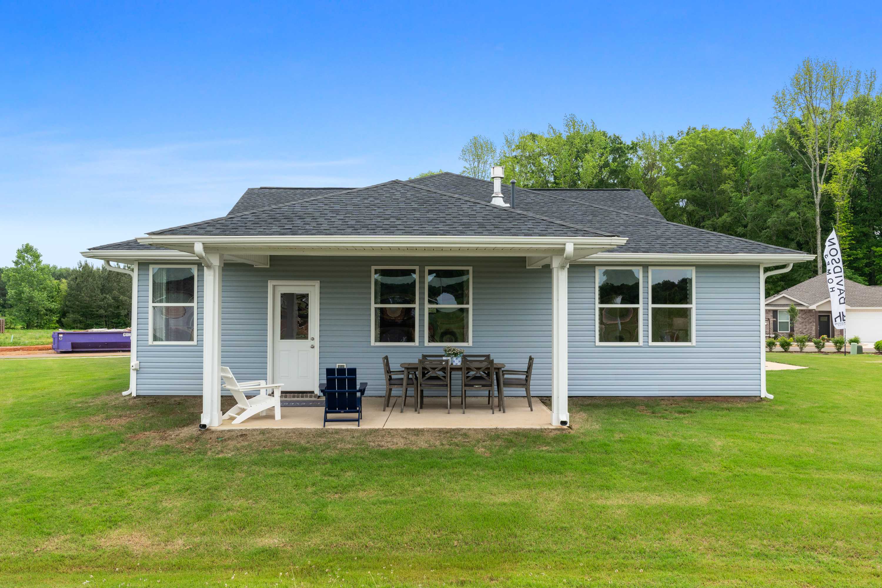 Covered back porch with Adirondack chairs and dining set on light blue home at Forest Glen in Hazel Green, Alabama