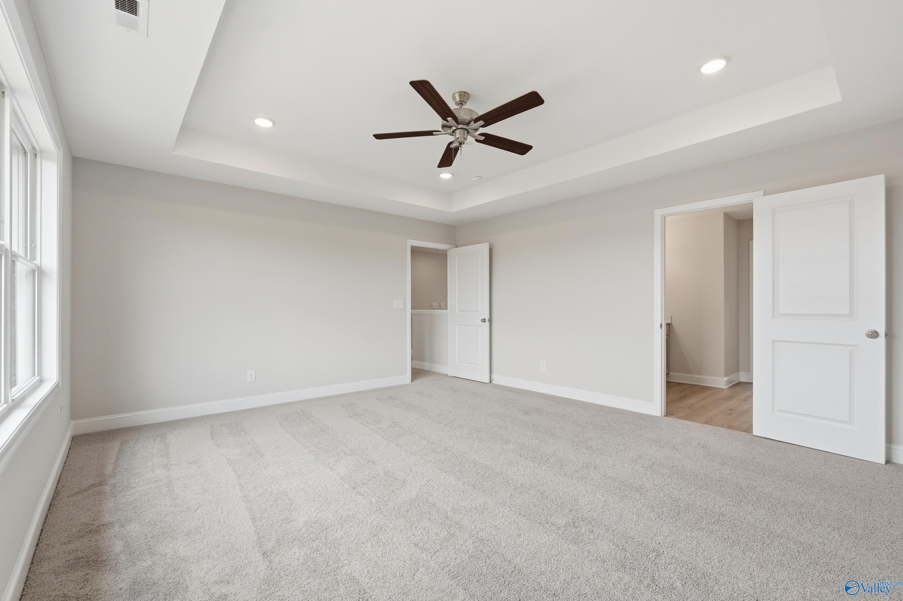 Spacious master bedroom with tray ceiling, ceiling fan, and en-suite door in Davidson Homes The Shelby B, New Market, Alabama