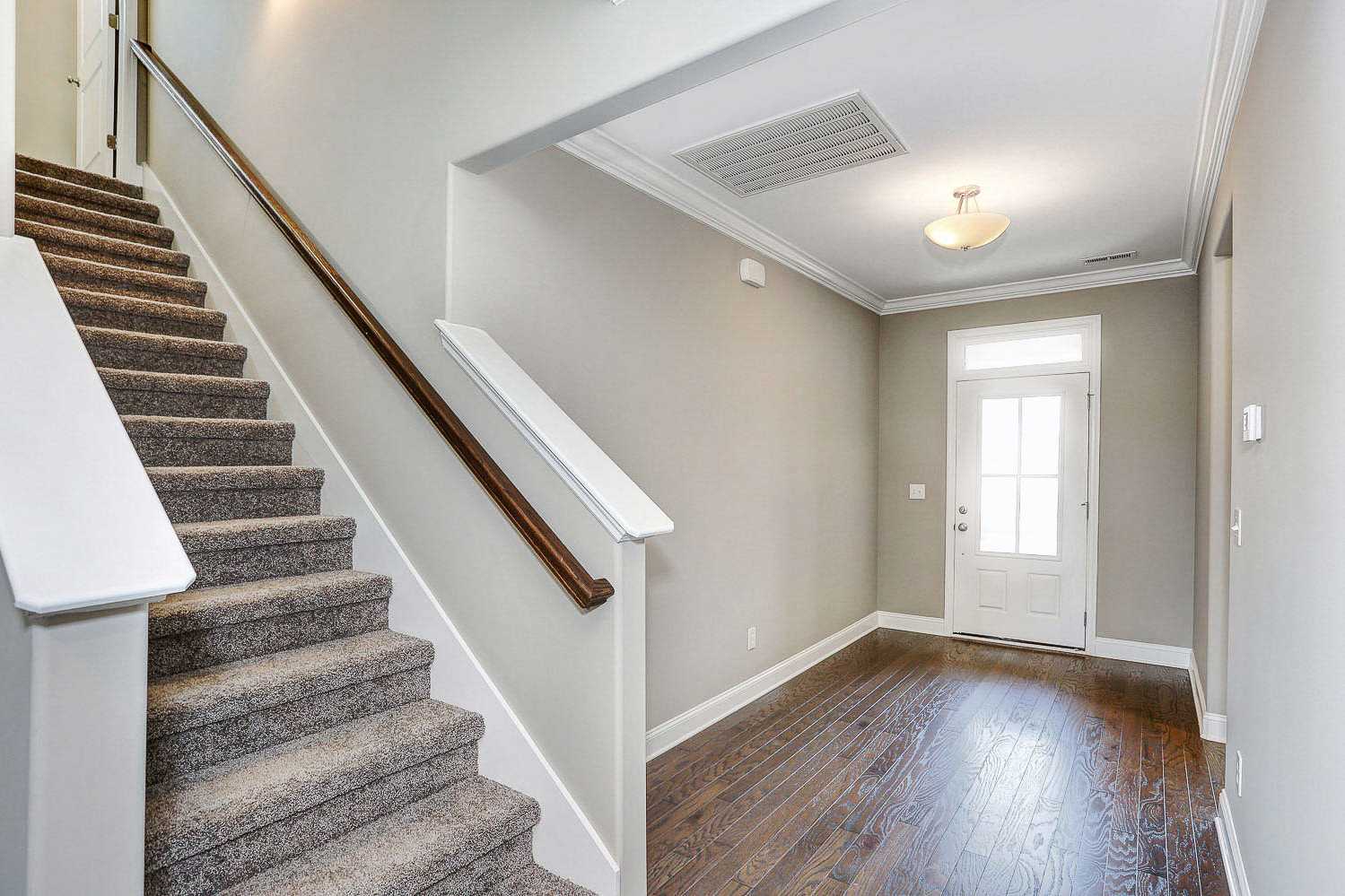 Spacious entry foyer and carpeted staircase in The Montgomery home by Davidson Homes, hardwood floors, neutral gray walls