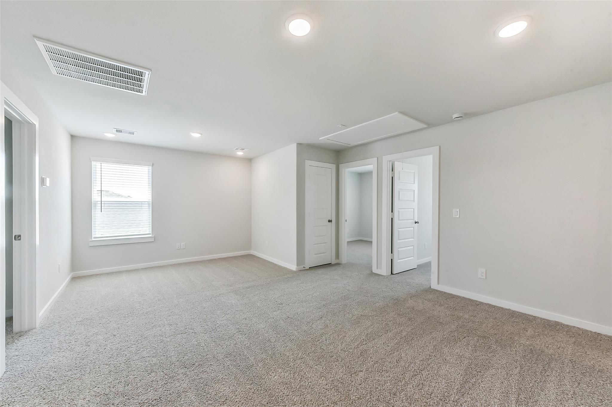 Bright upstairs loft with gray carpet, white walls, recessed lights, and doorways in Davidson Homes The Brazos E, Magnolia, TX