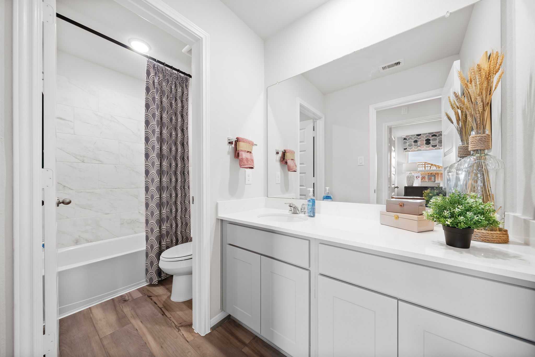 Spacious bathroom at Hill & Dale Ranch in Splendora Texas featuring white subway tile, alcove tub with purple curtain, double vanity
