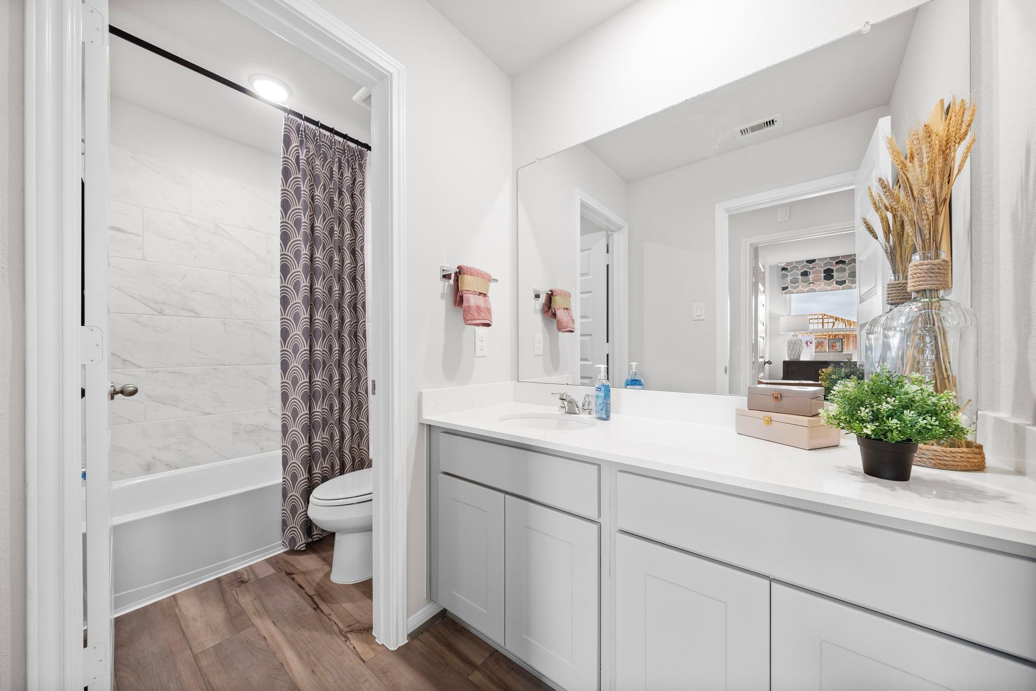 Spacious bathroom at Hill & Dale Ranch in Splendora Texas featuring white subway tile, alcove tub with purple curtain, double vanity