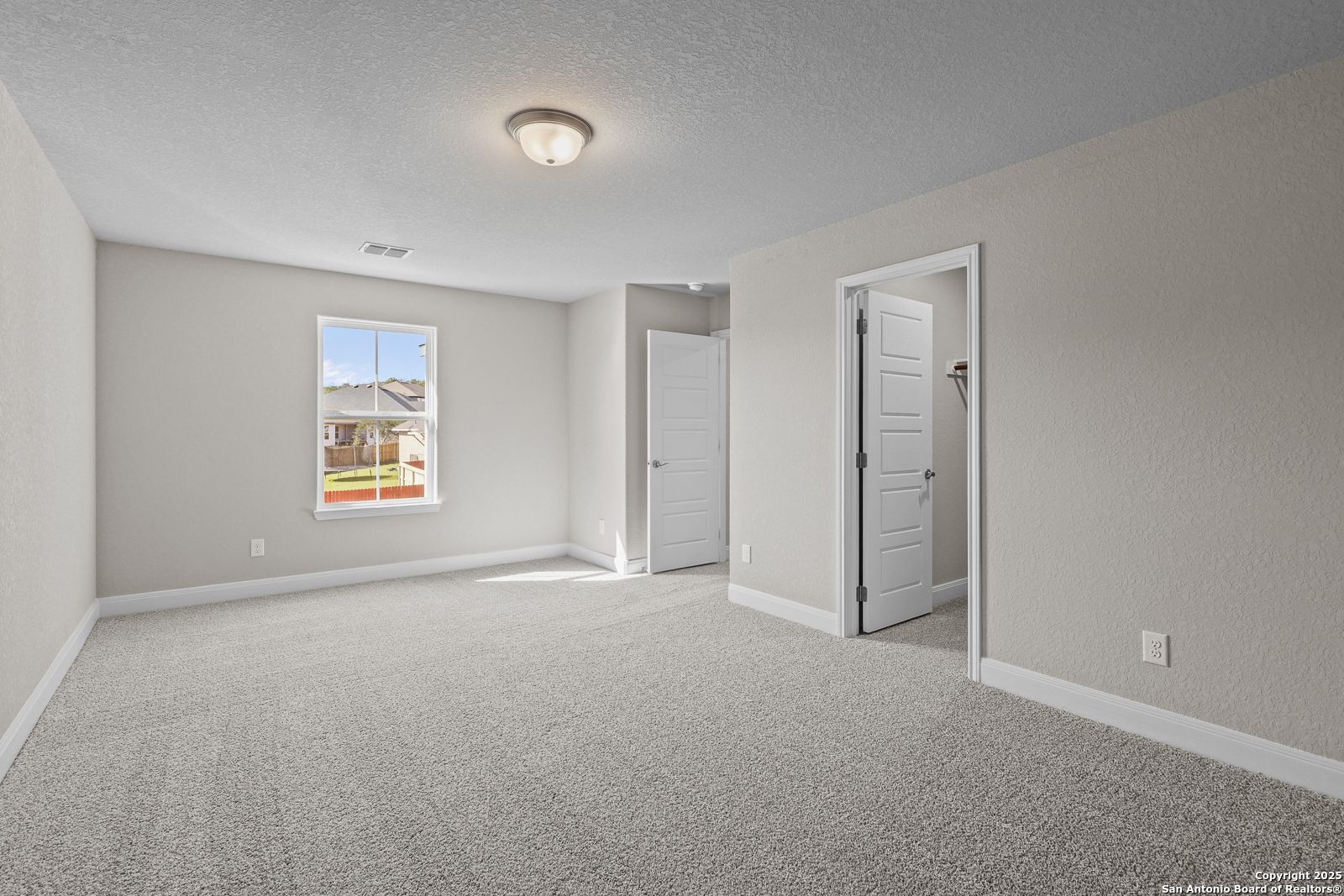 Spacious secondary bedroom with neutral walls, gray carpet, window view, and adjacent doors in Davidson Homes The Jennings G, Castroville, Texas
