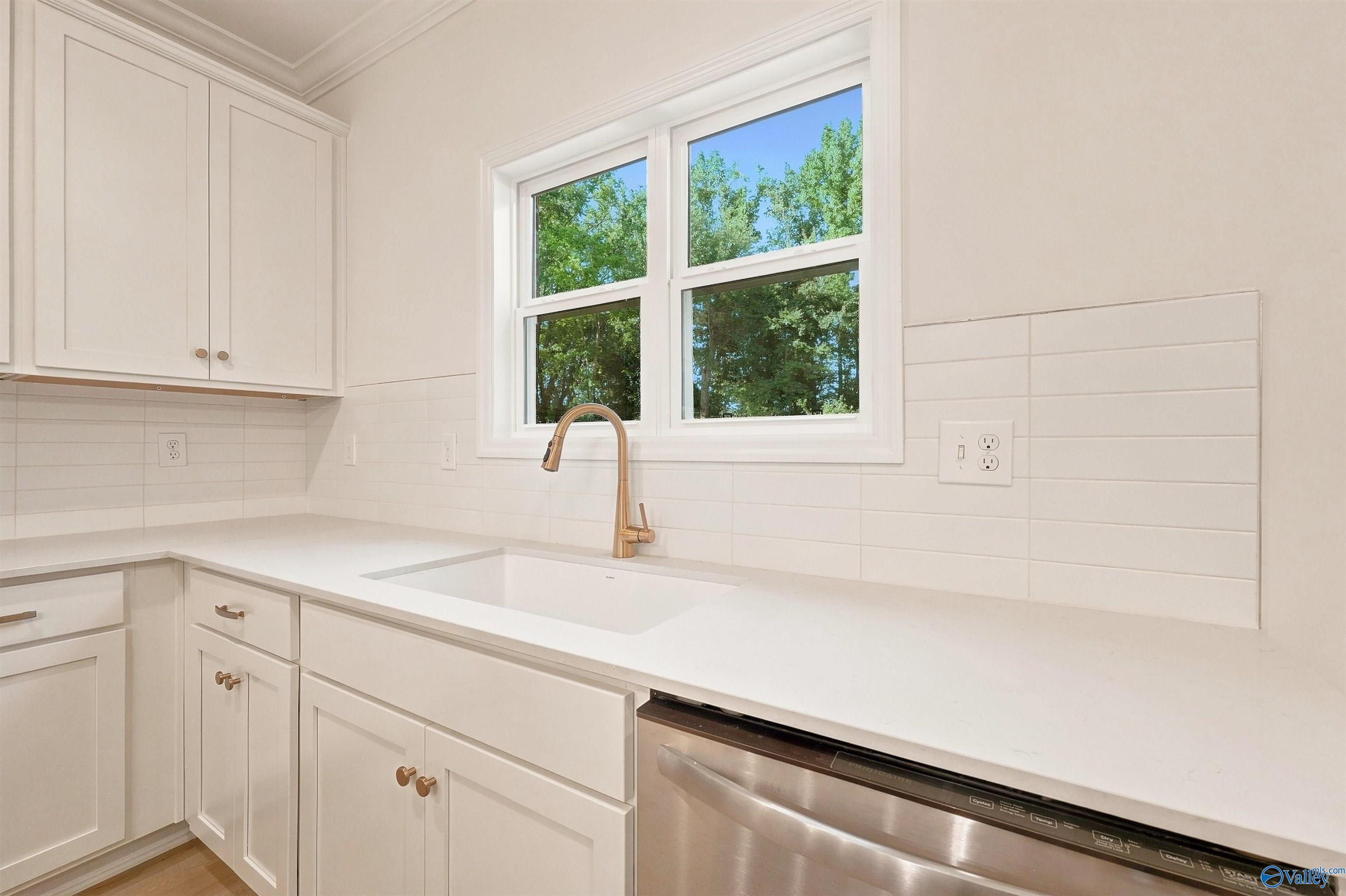 Modern kitchen with white shaker cabinets, farmhouse sink, and gold faucet in The Chelsea C home in Creek Grove, Alabama.