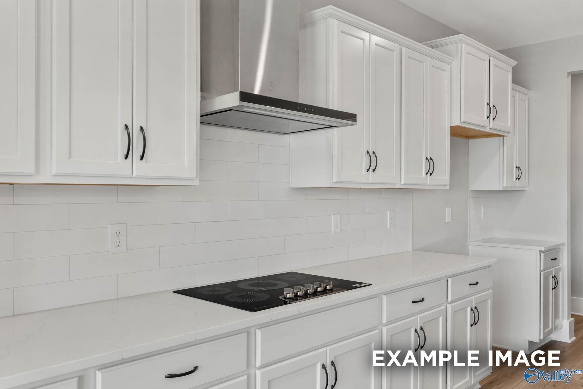 Modern white kitchen with quartz countertops, subway tile backsplash, and stainless steel hood in The Finleigh, Briercreek.