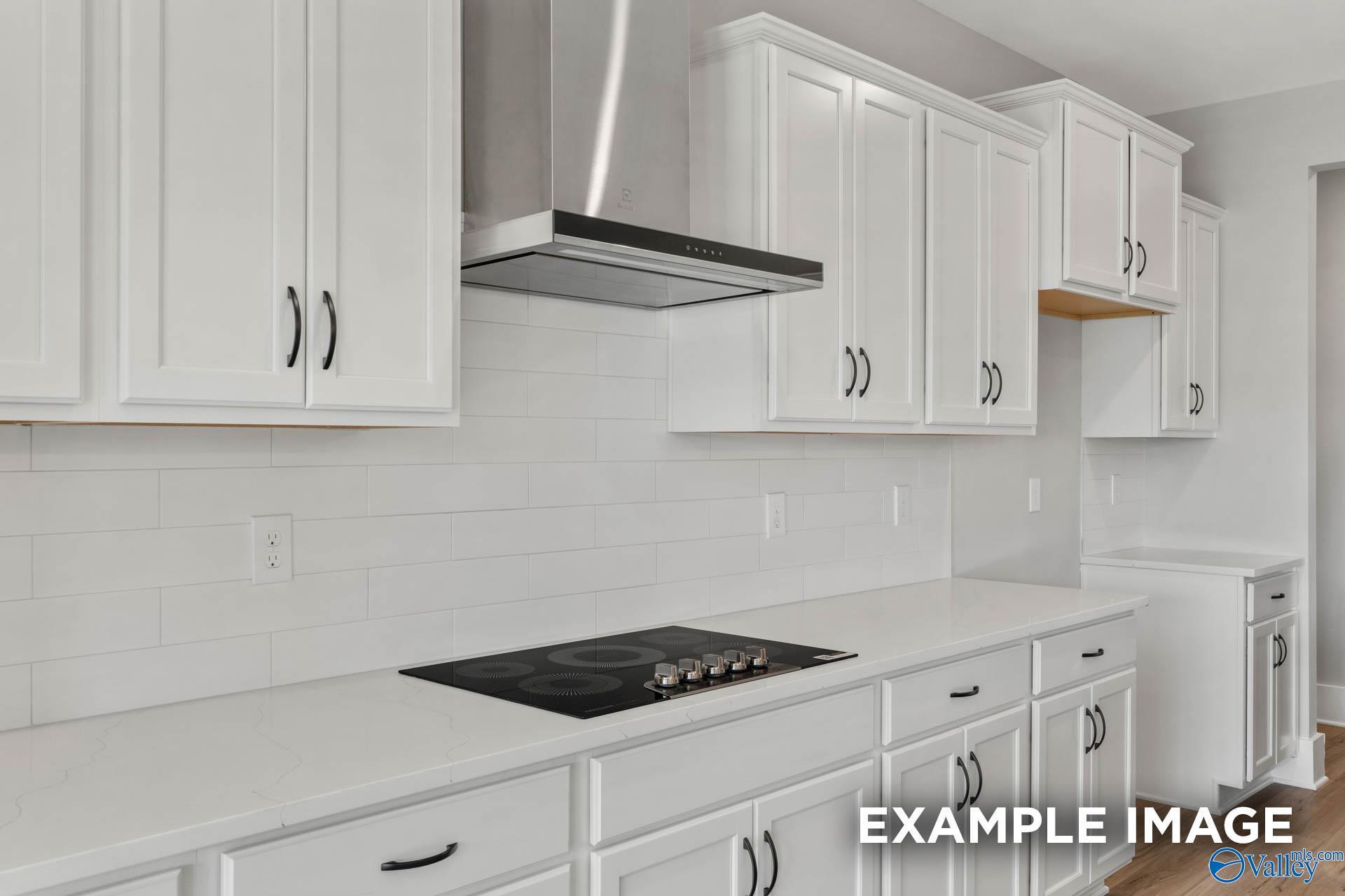 Modern white kitchen with quartz countertops, subway tile backsplash, and stainless steel hood in The Finleigh, Briercreek.