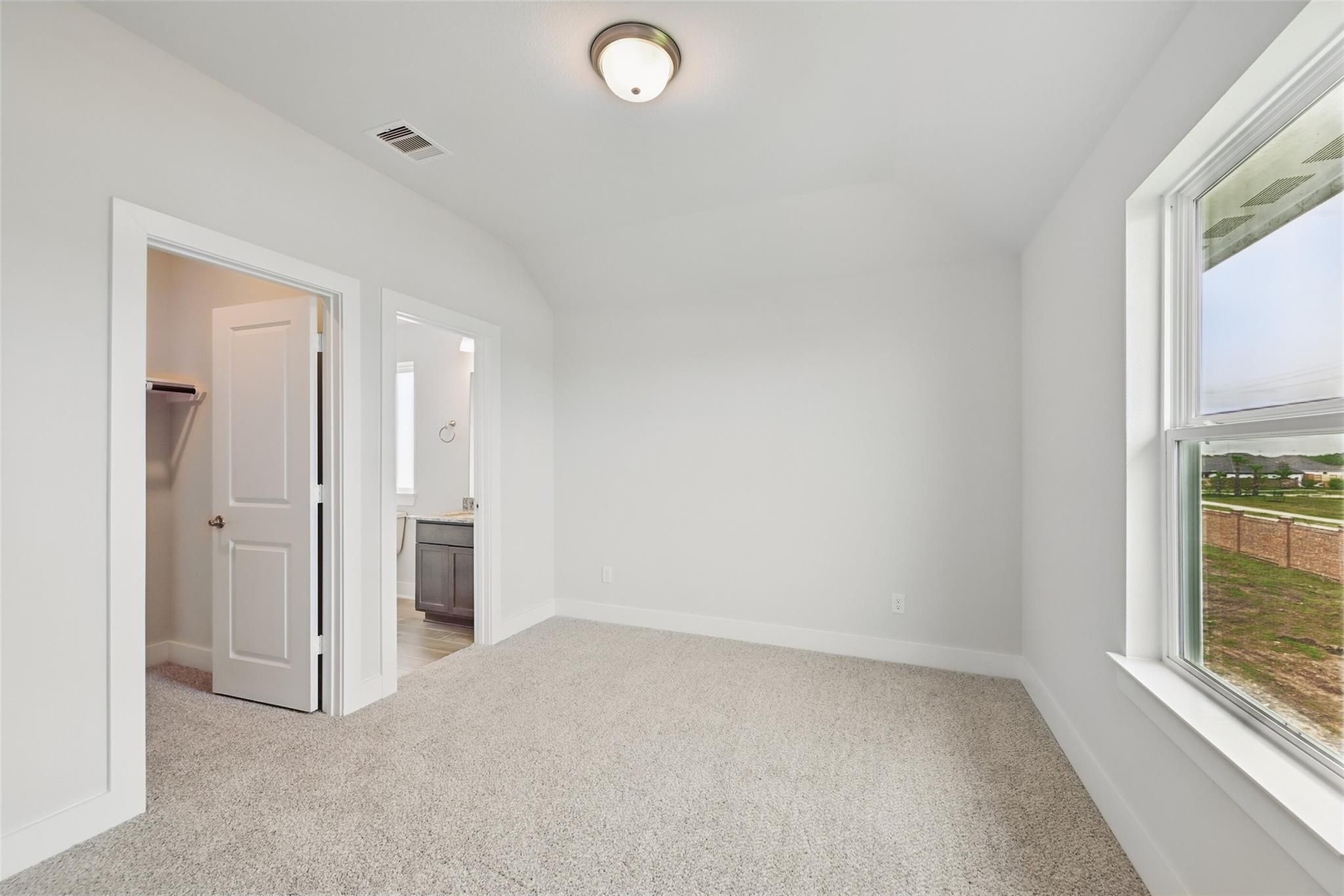 Bright secondary bedroom with white walls, beige carpet, en-suite bath, closet, and field view window in Davidson Homes The Philip A, Lago Mar