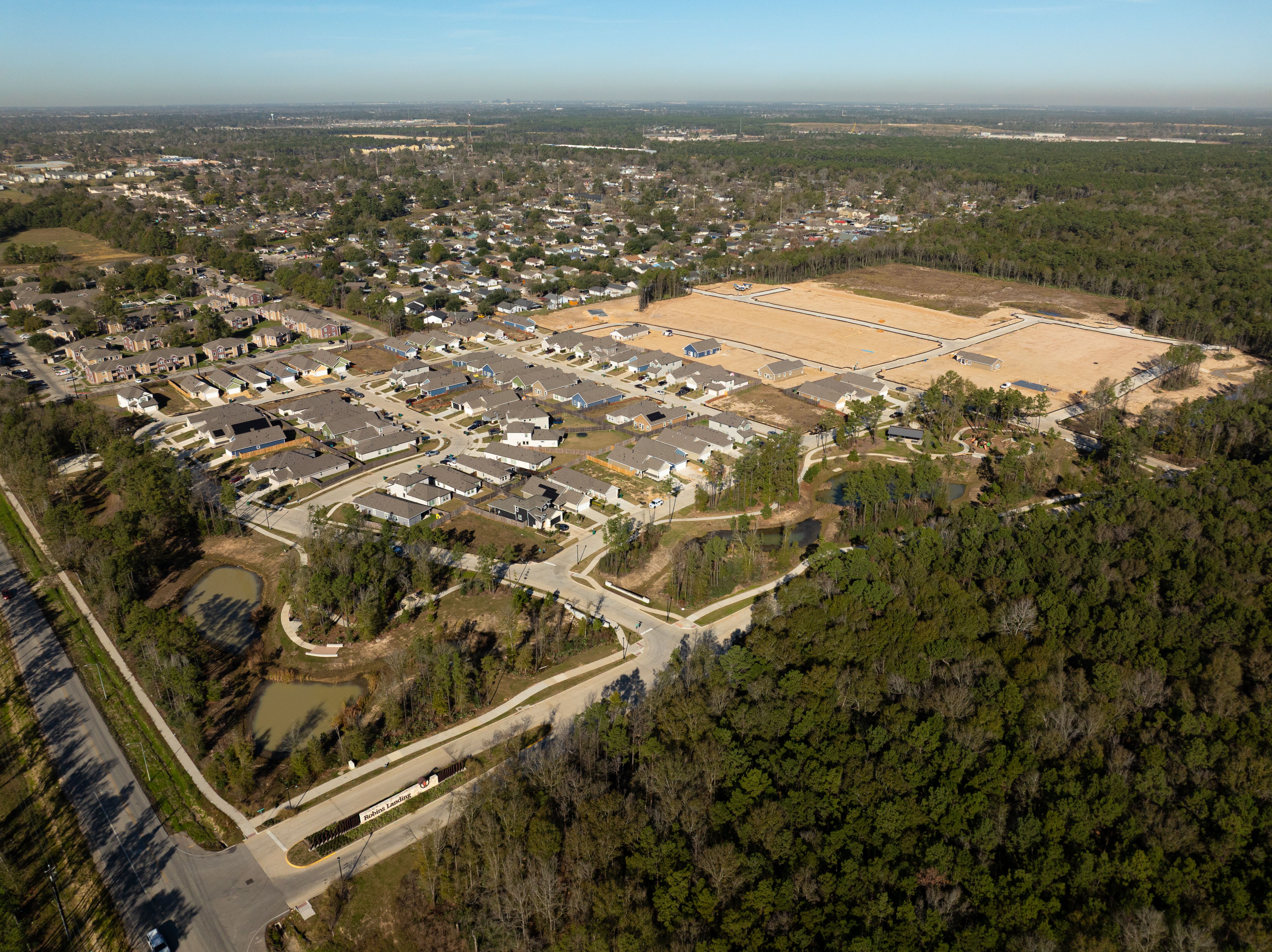 Aerial view of Robins Landing neighborhood in Houston TX with new Davidson Homes, construction lots, and surrounding pines