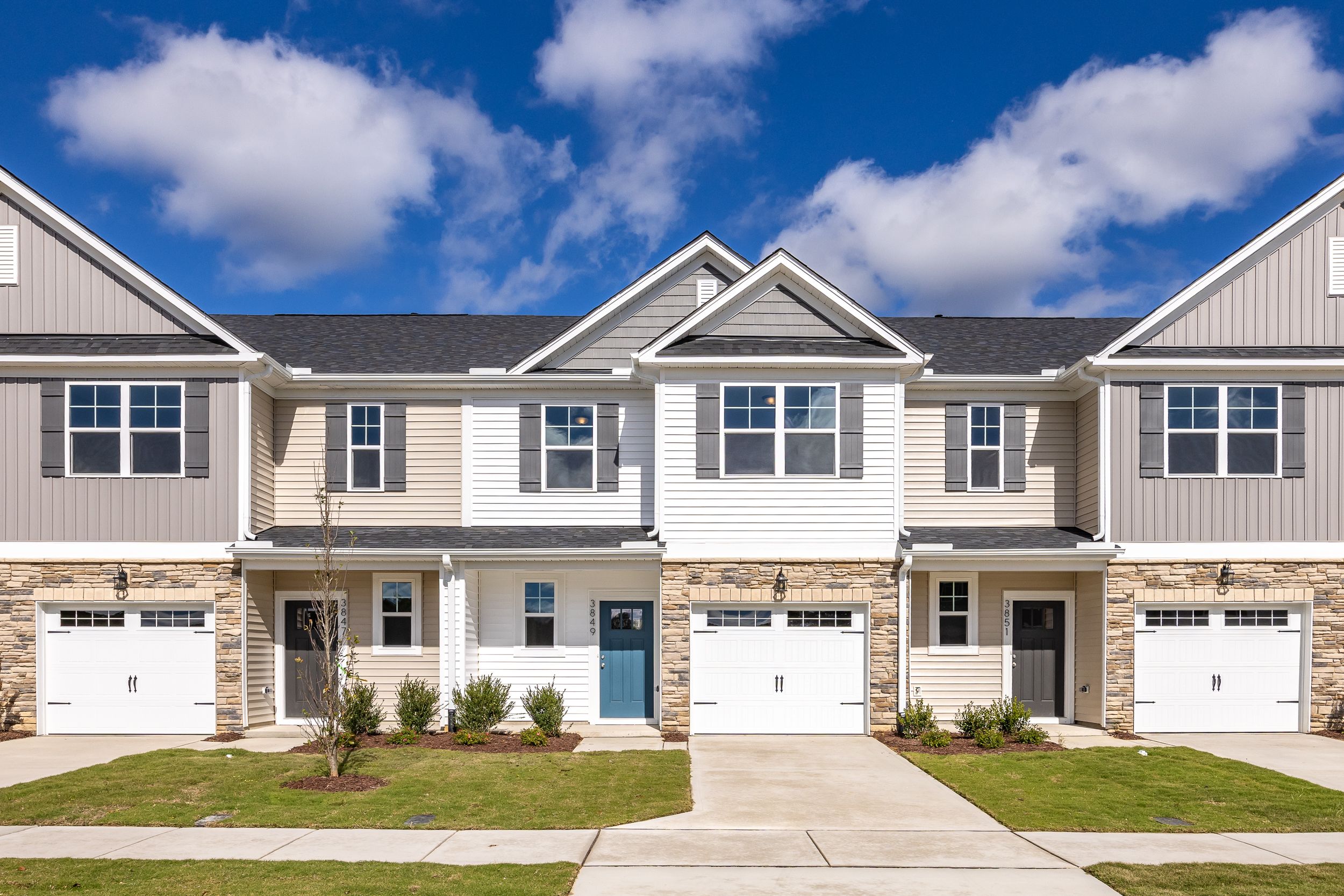 Modern townhome exterior at Springvale in Fuquay-Varina, NC, featuring stone accents, siding, and attached garages.