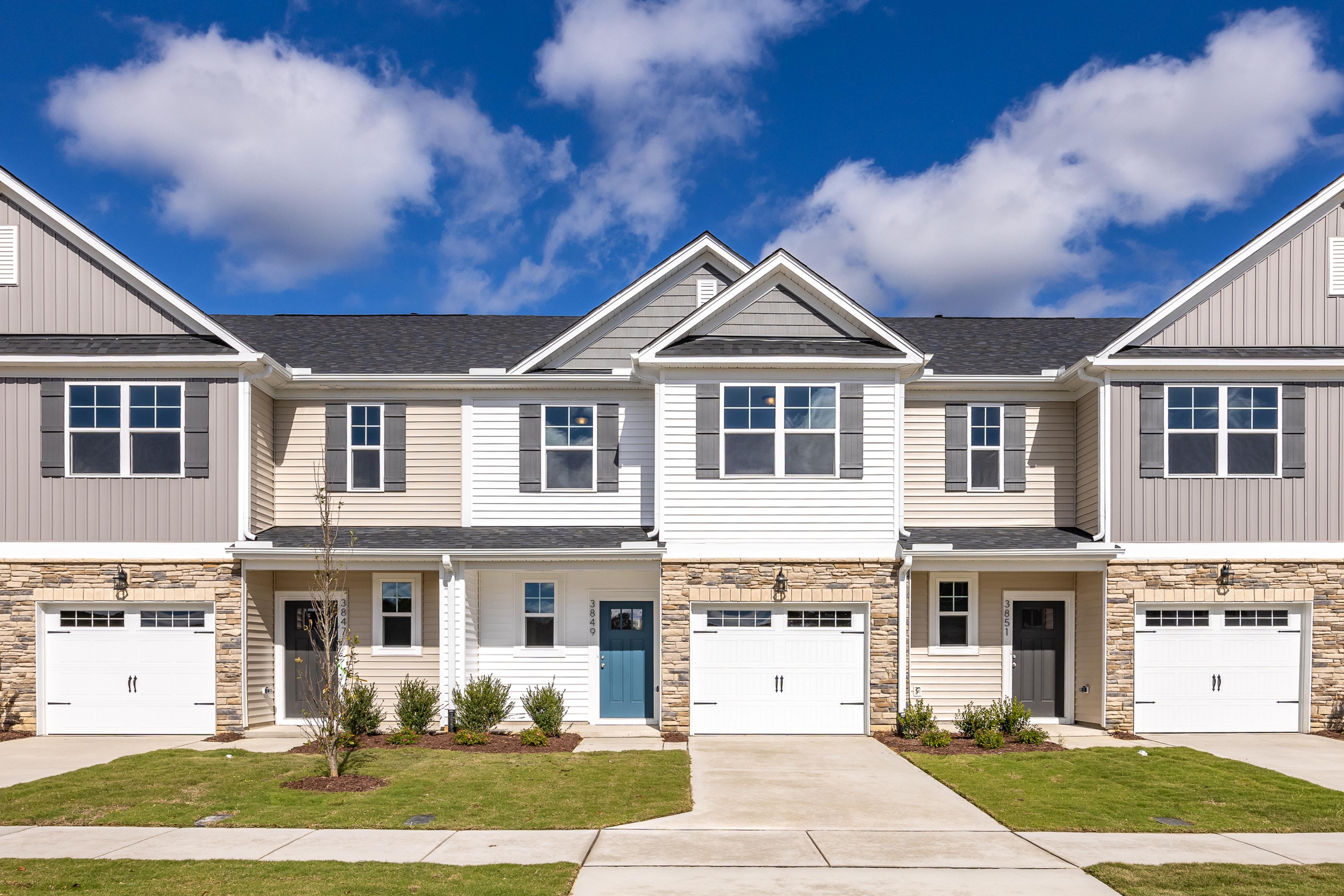 Modern townhome exterior at Springvale in Fuquay-Varina, NC, featuring stone accents, siding, and attached garages.