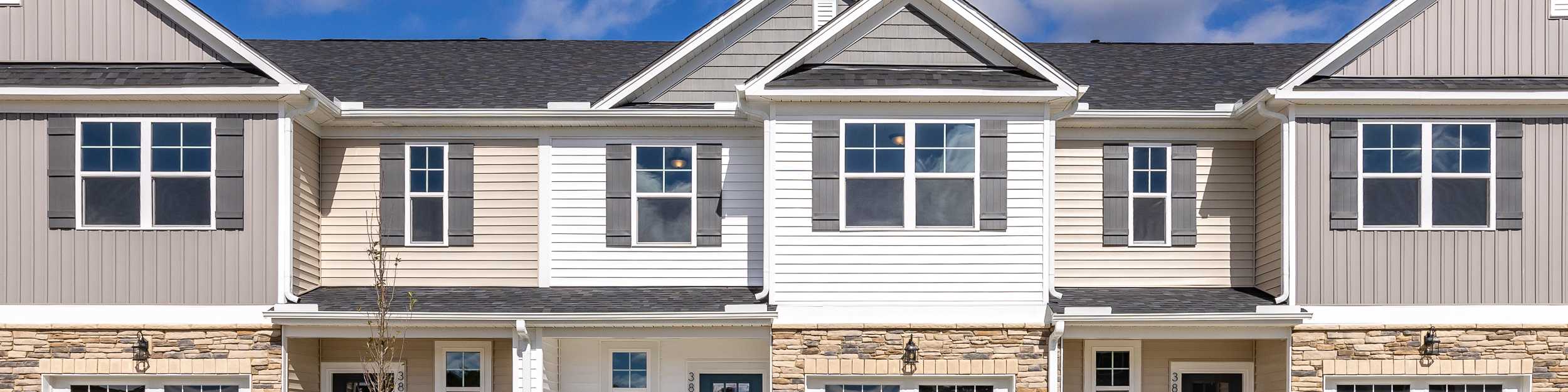 Modern townhome exterior at Springvale in Fuquay-Varina, NC, featuring stone accents, siding, and attached garages.