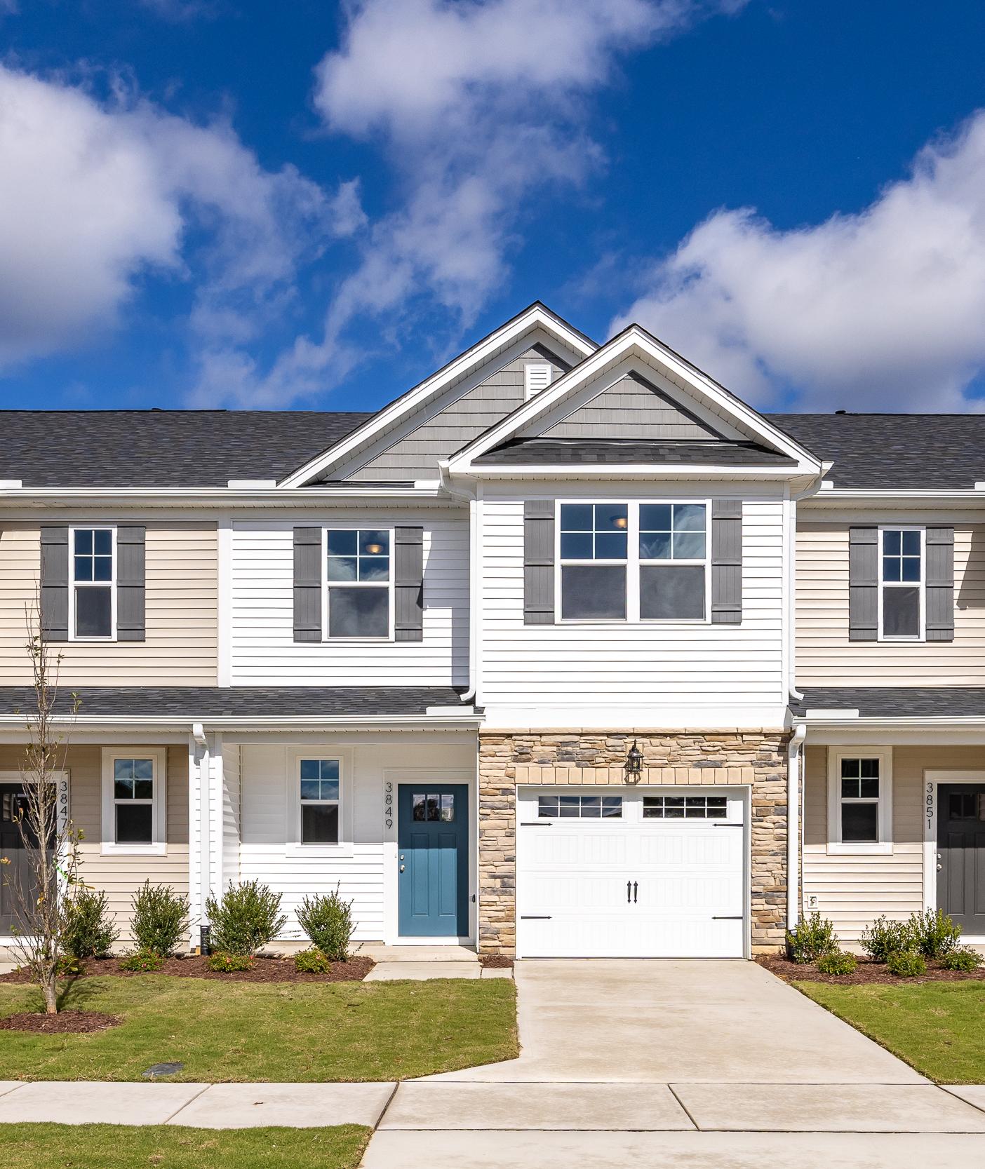 Modern townhome exterior at Springvale in Fuquay-Varina, NC, featuring stone accents, siding, and attached garages.