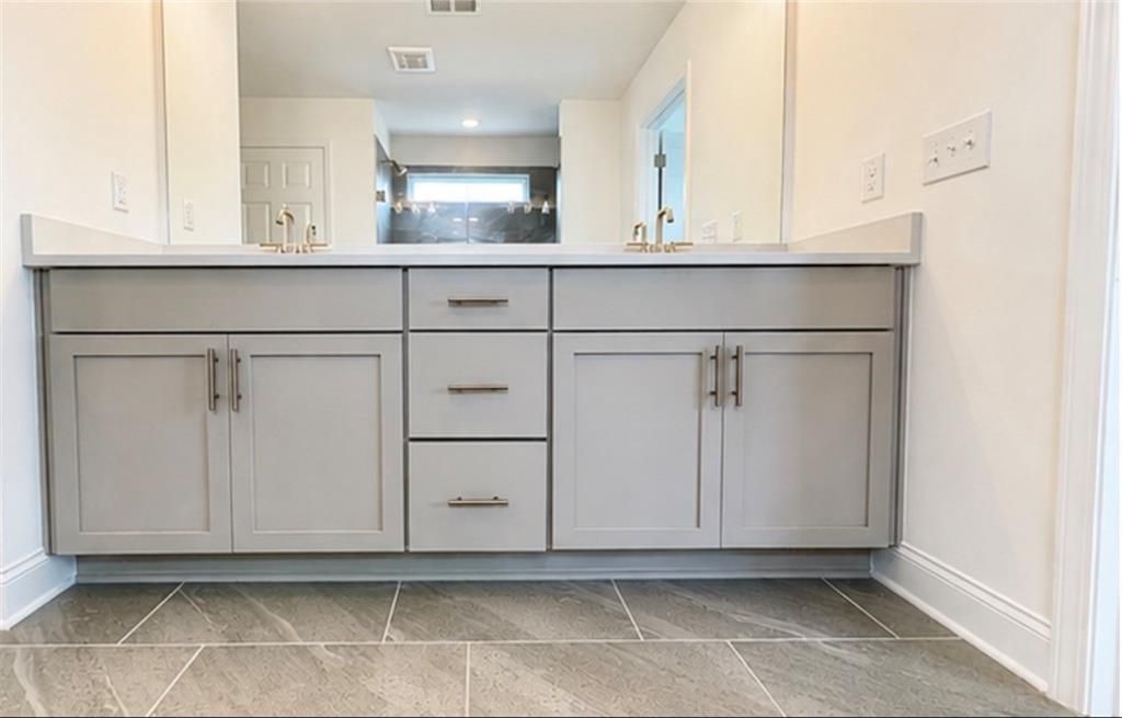 Double vanity with gray cabinets and stone countertops in The Hickory C floor plan at Wehunt Meadows, Hoschton, Georgia.