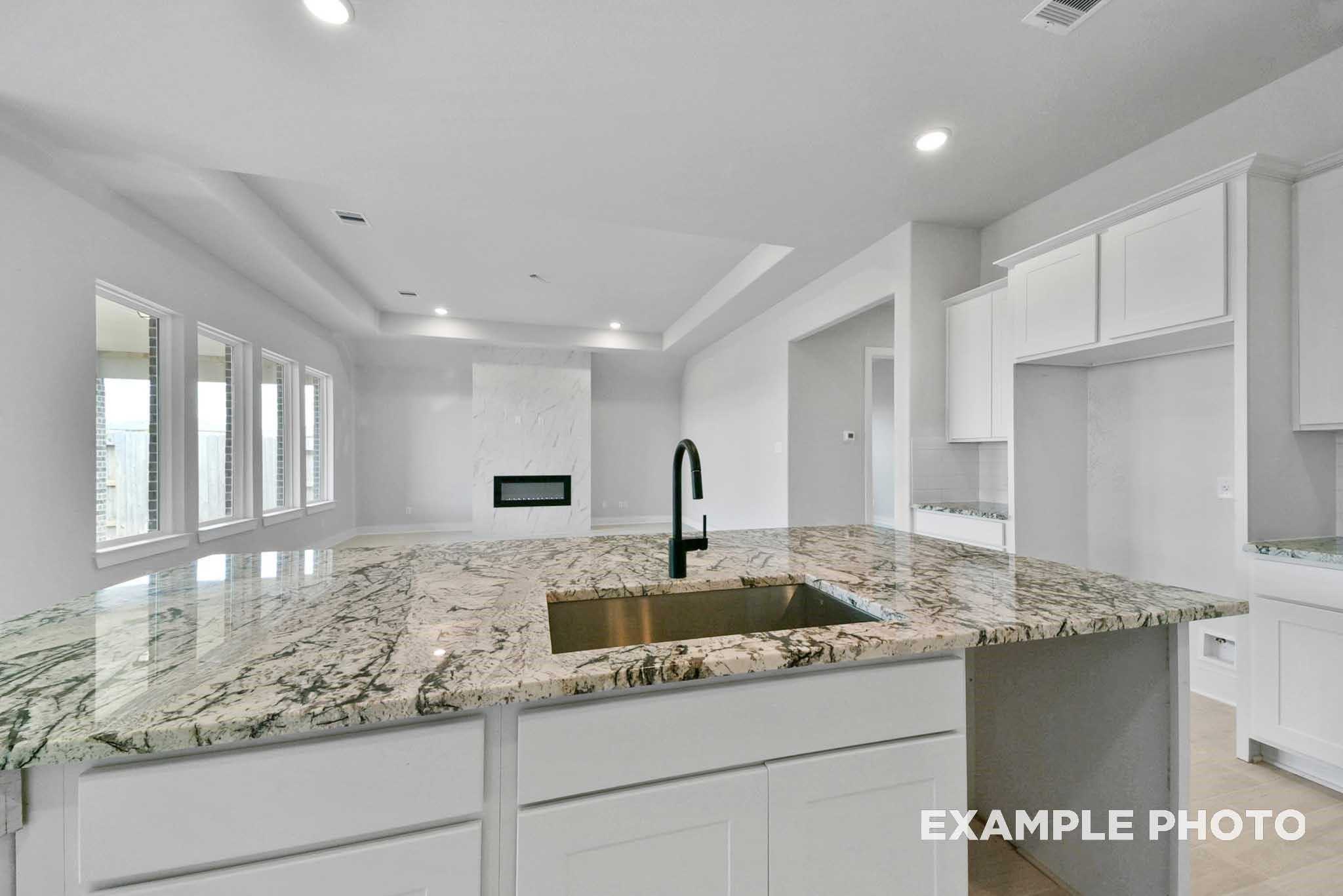 Modern granite kitchen island with undermount sink and white shaker cabinets in open-concept space of Davidson Homes The George A, Lago Mar, Texas City