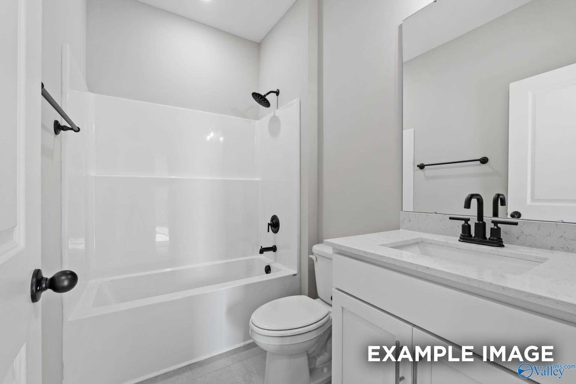 Modern guest bathroom featuring white bathtub shower combo, single vanity sink, and large mirror in The Montgomery B by Davidson Homes, Toney, Alabama