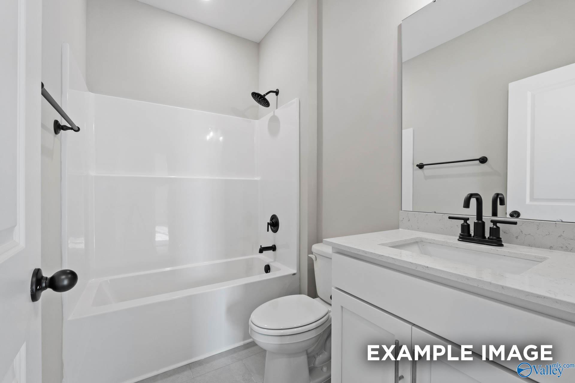 Modern full bathroom with white vanity, quartz countertop, and matte black fixtures in The Montgomery B, Decatur, Alabama.