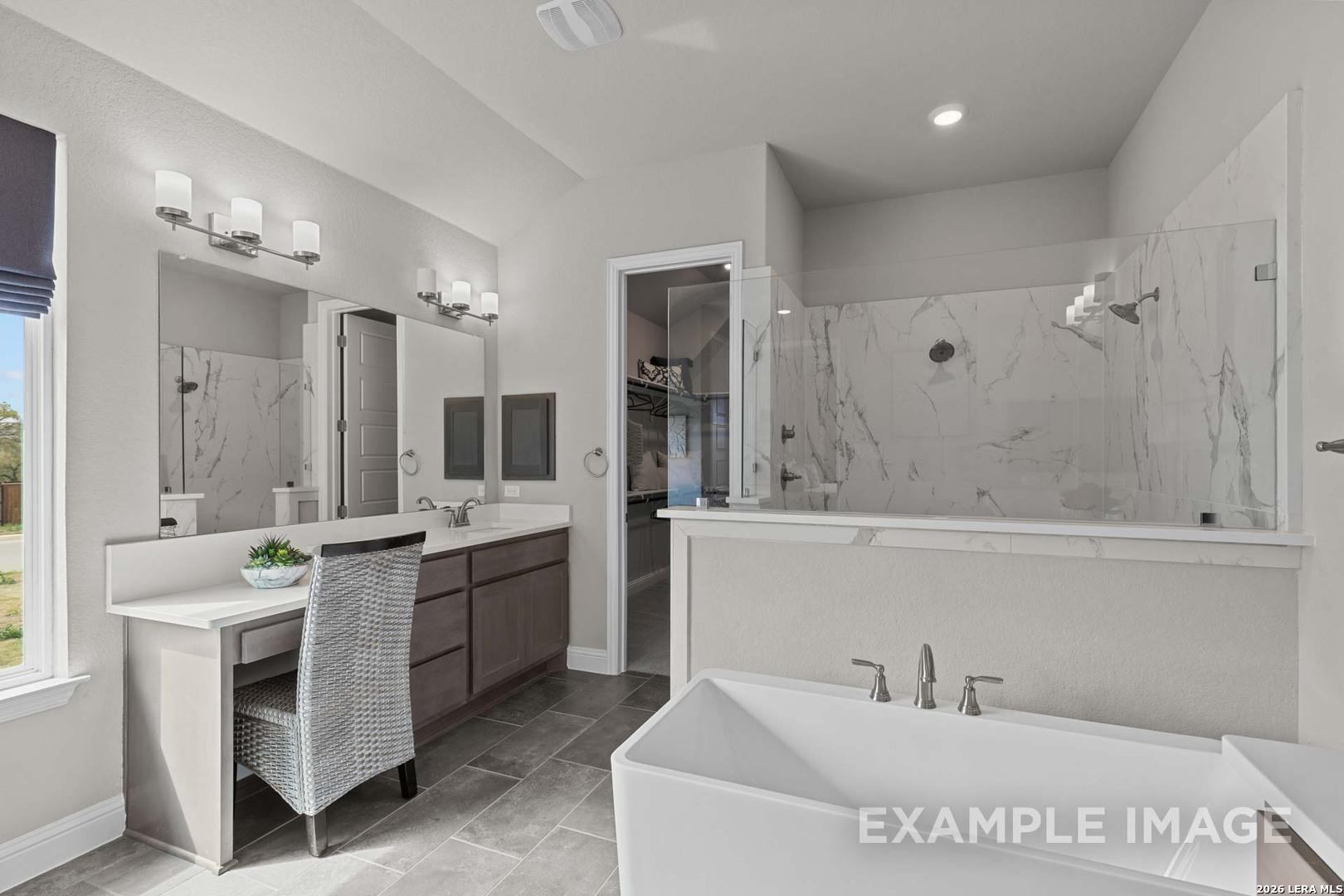 Modern master bathroom with soaking tub, glass-enclosed shower, and vanity in The Garner C floor plan, Castroville, TX.