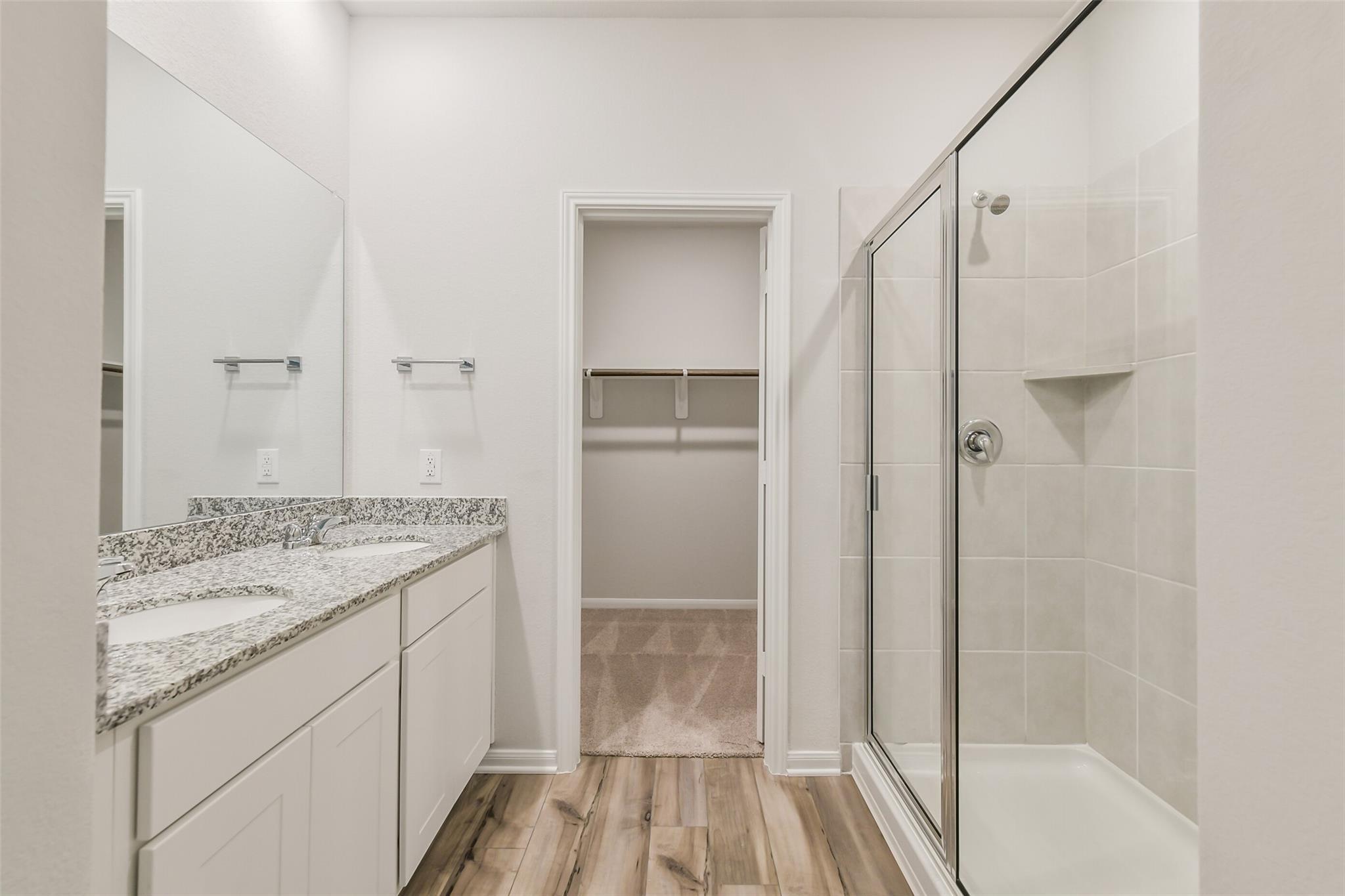 Modern master bath with double granite vanity, frameless glass shower, and walk-in closet in Davidson Homes The Brazos F, Conroe, Texas