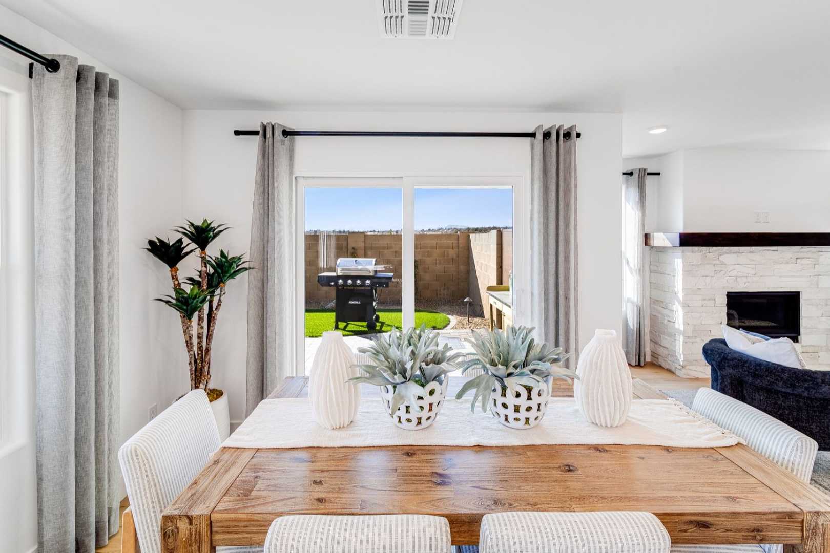 Spacious dining area in The Wilmington Davidson Homes design featuring wooden table, potted succulents, and sliding doors to backyard patio