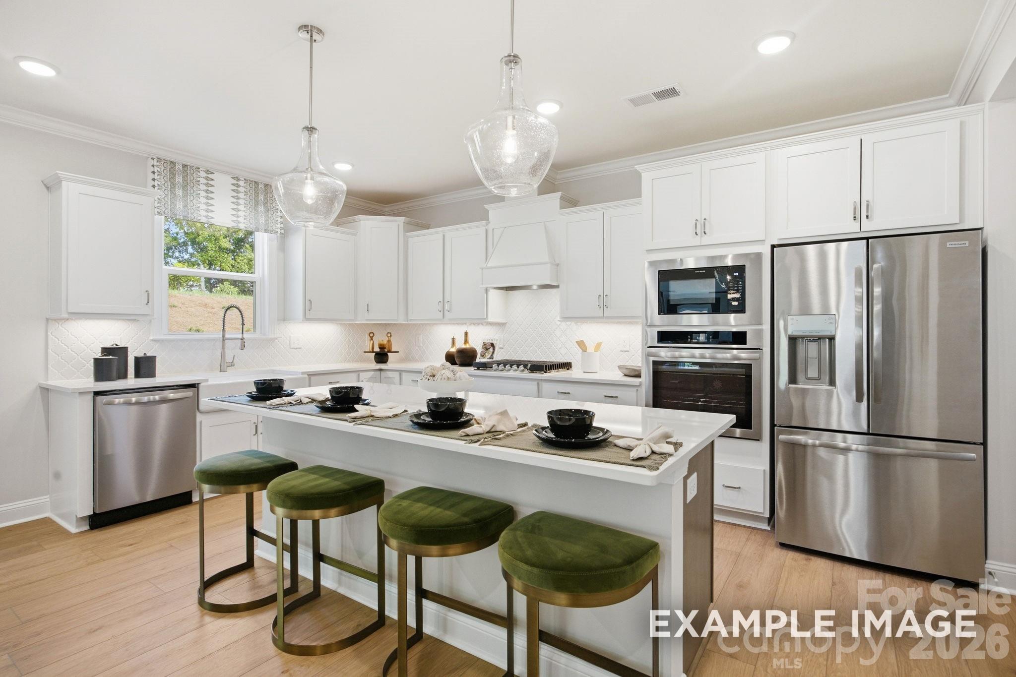 Modern white kitchen with island, pendant lighting, and stainless appliances in Hickory B II plan, Windgate, Mooresville.