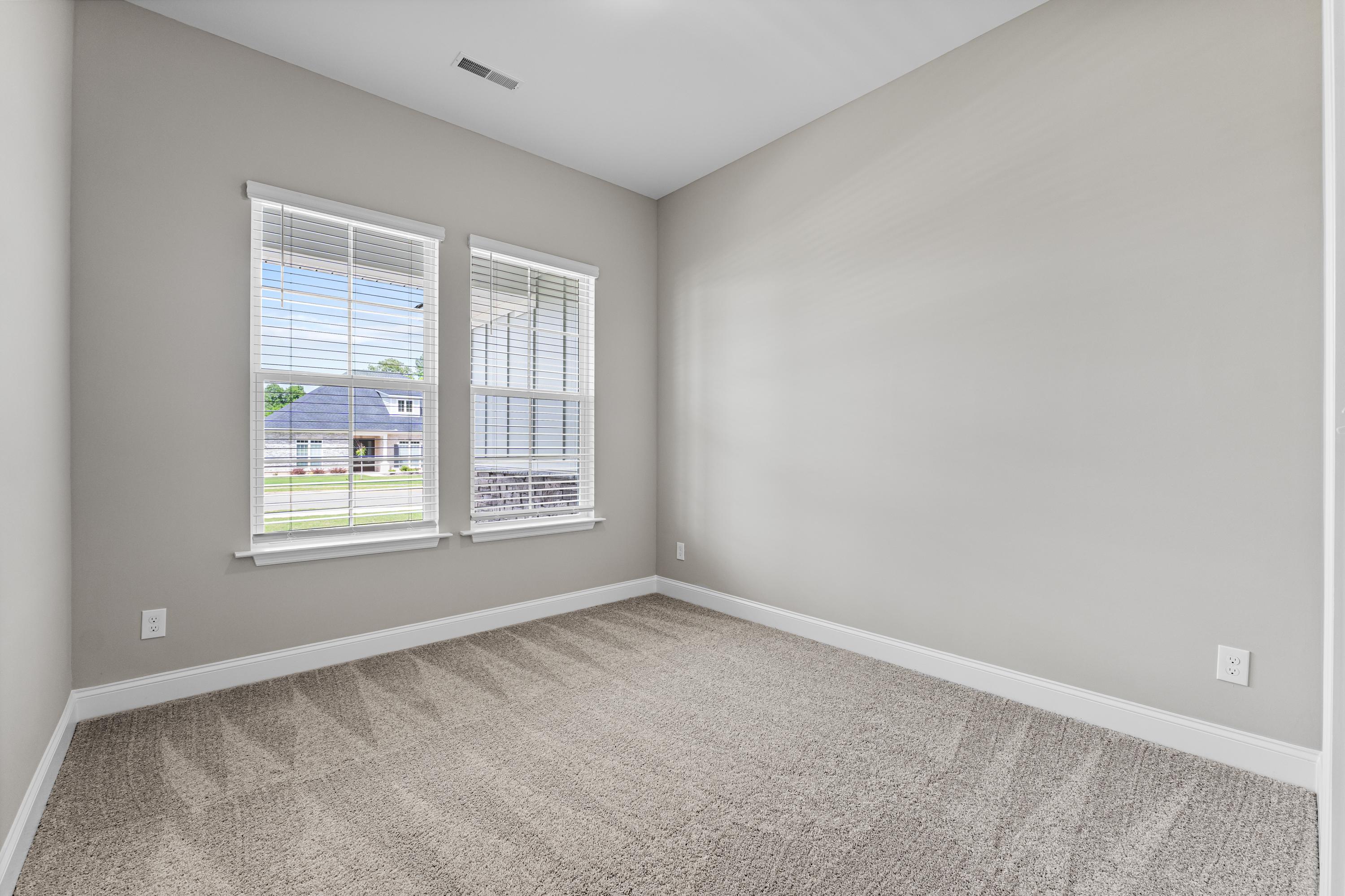 Spacious secondary bedroom in The Arcadia B by Evermore Homes, light gray walls, beige carpet, double windows with suburban view