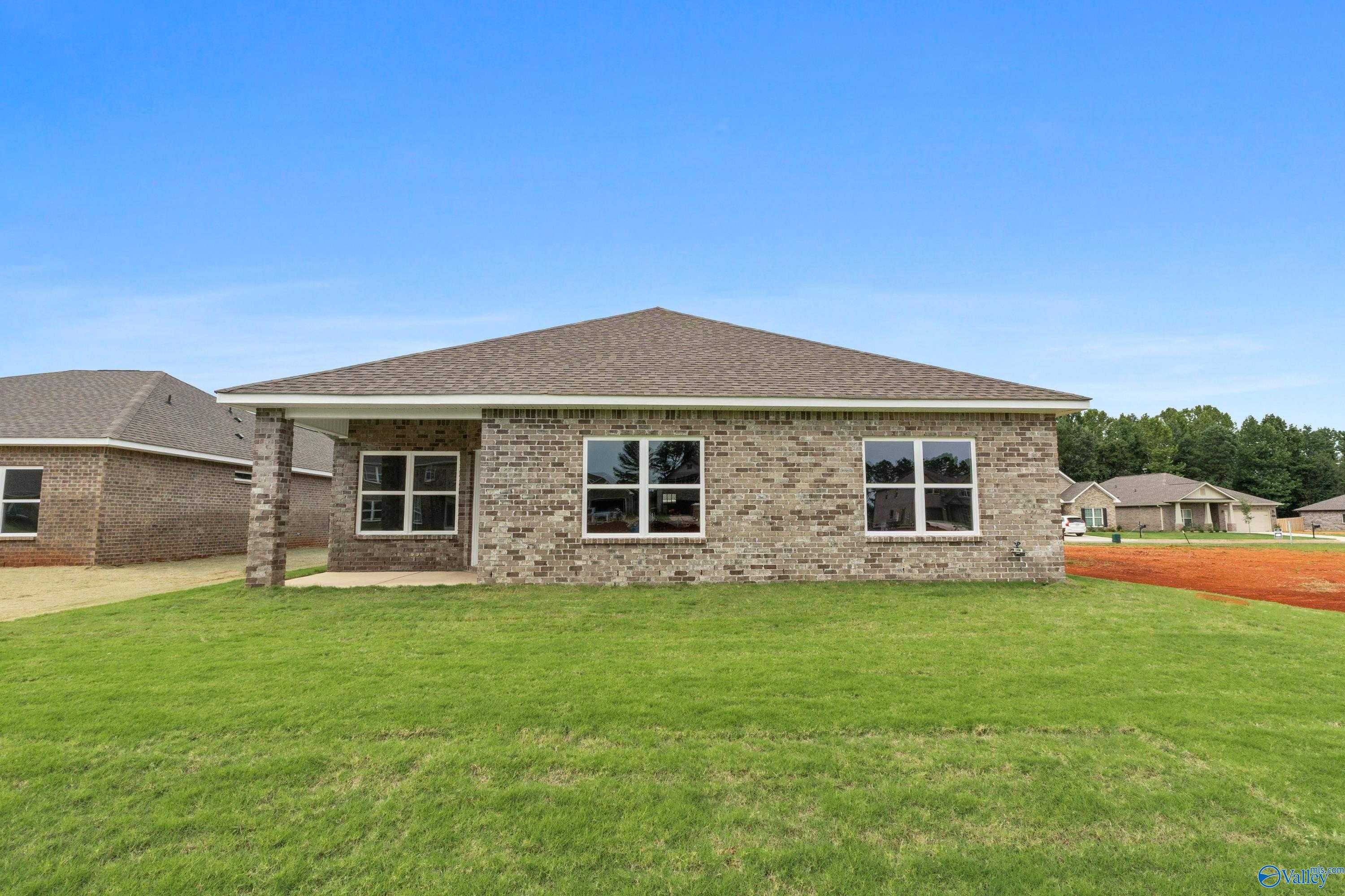 Single-story 4-bedroom brick home with 2-car garage, large windows, and green lawn in Ricketts Farm, Athens, Alabama by Davidson Homes