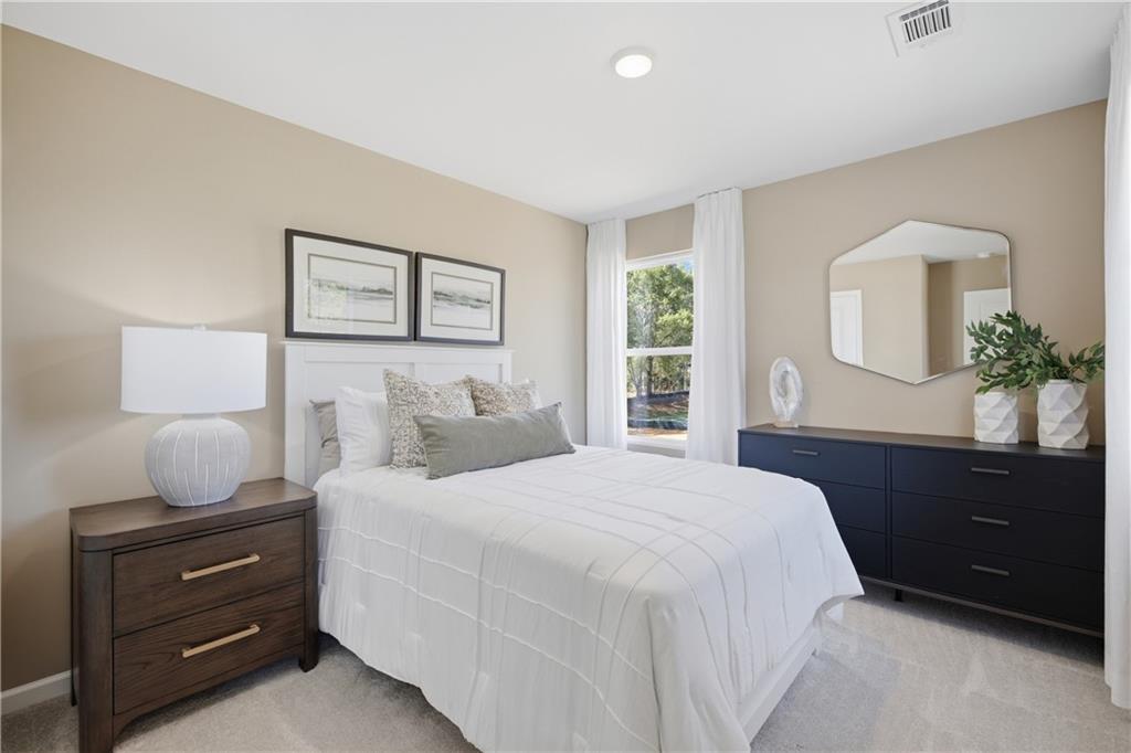 Bright neutral bedroom with white bedding, wood nightstand, and navy dresser in Davidson Homes Sinclair B, Cartersville, Georgia