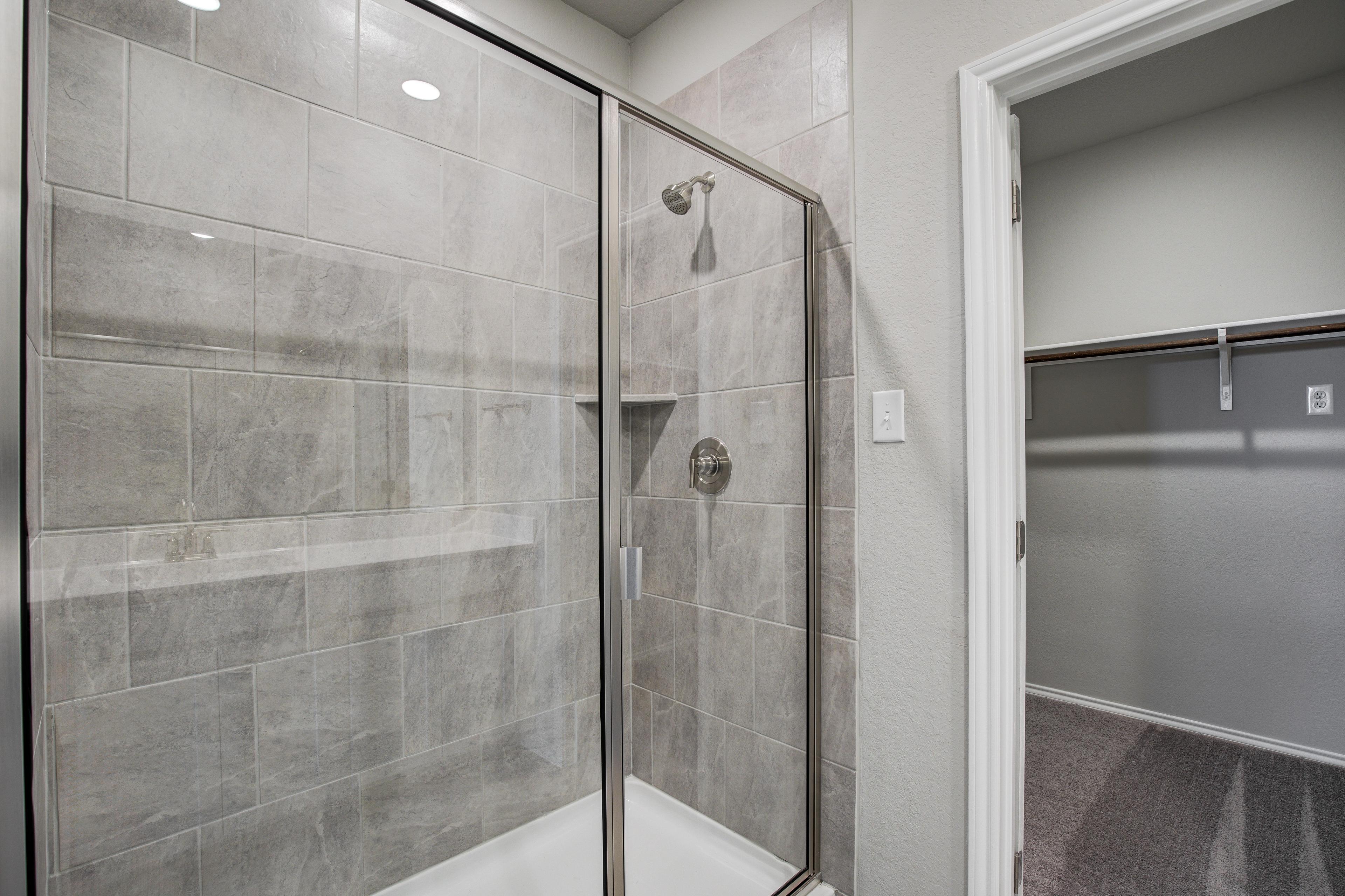 Spacious master bathroom in The Blanco C featuring frameless glass shower with gray subway tiles and walk-in closet