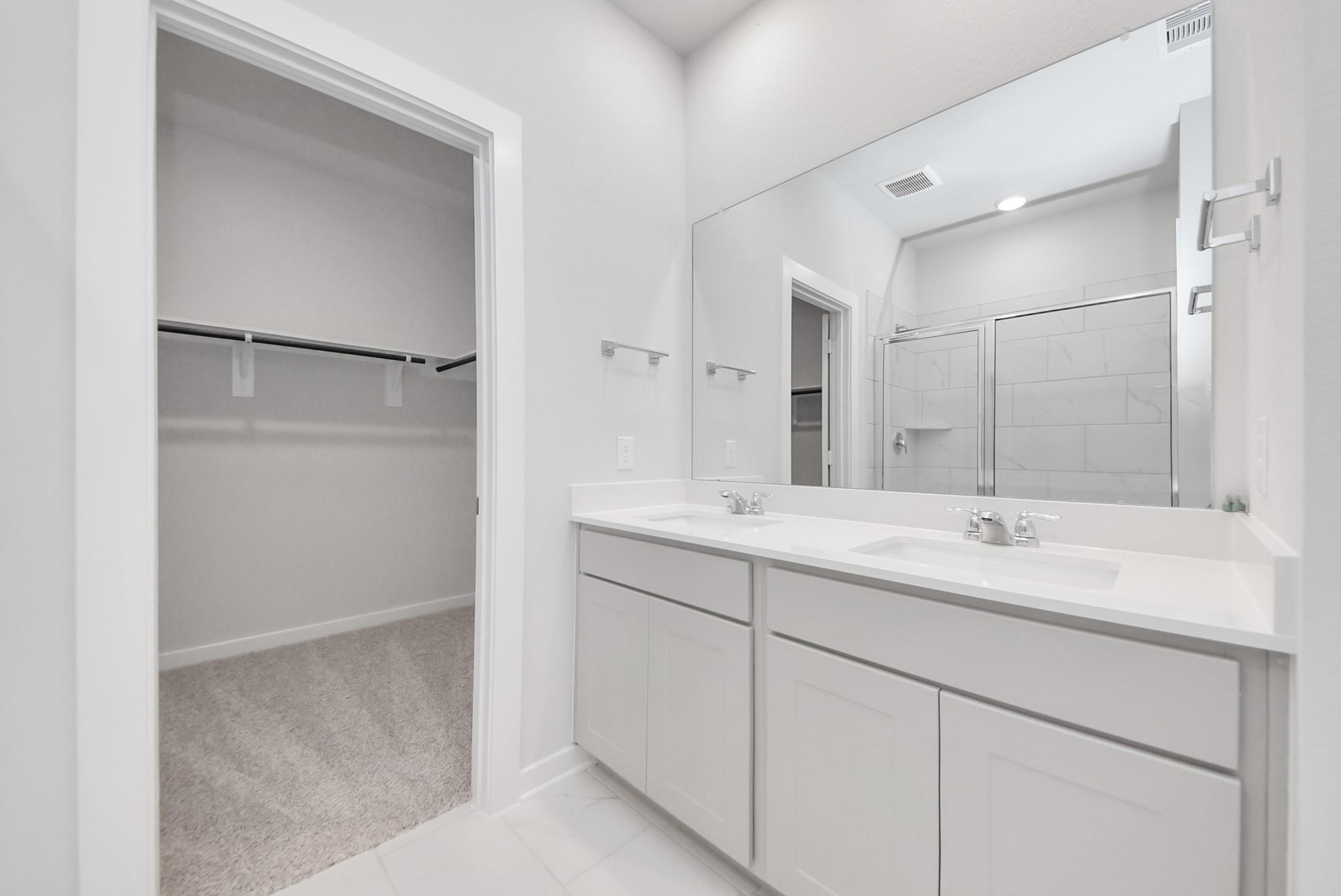 Modern primary bathroom with double vanity and walk-in closet in The Blanco F floor plan at Spring Branch Crossing, Conroe.